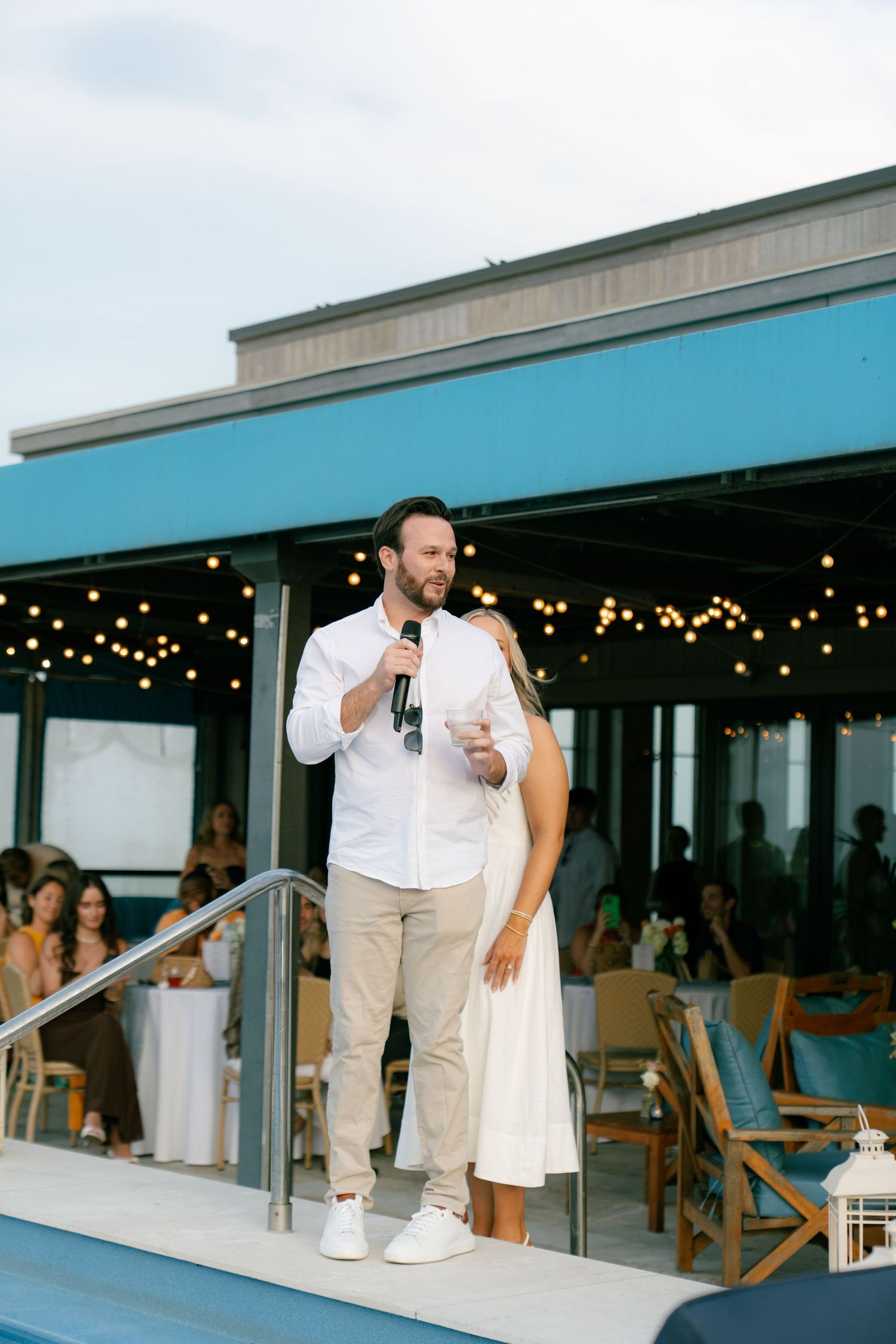 Wedding reception venue with string lights and coastal views at dusk.