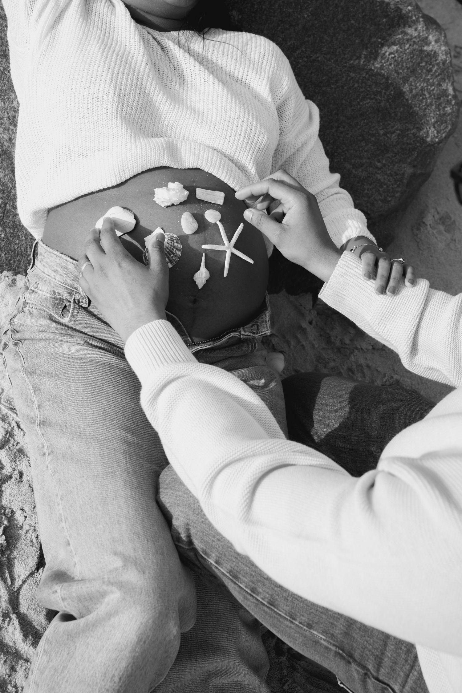 Close-up black and white images of hands holding and arranging small objects.