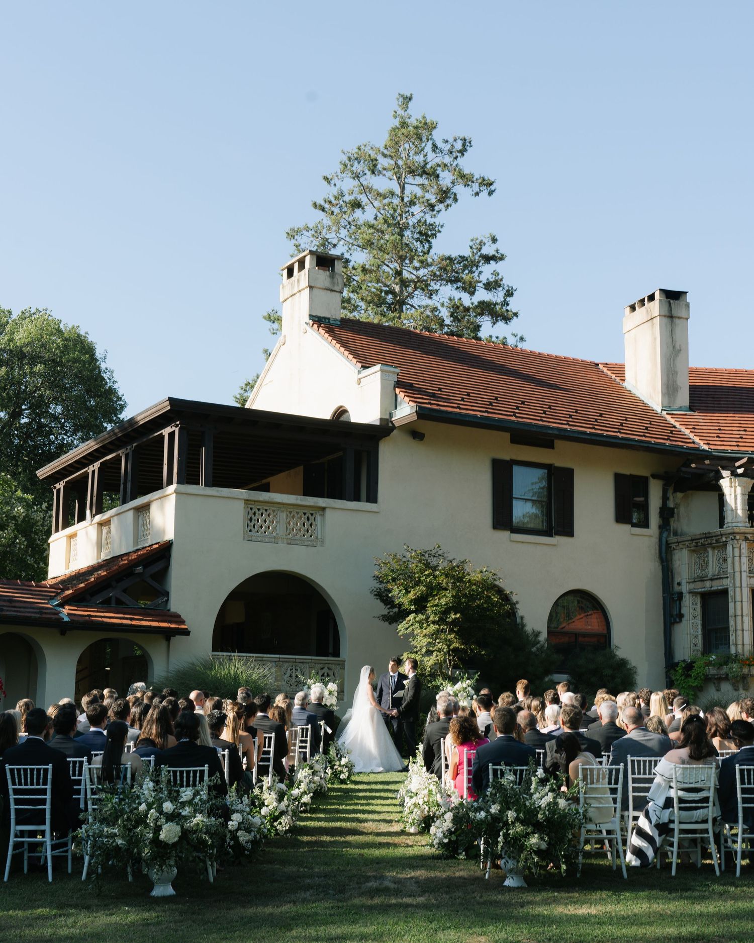 Outdoor wedding ceremony setup at elegant white Spanish-style venue with arched architecture.