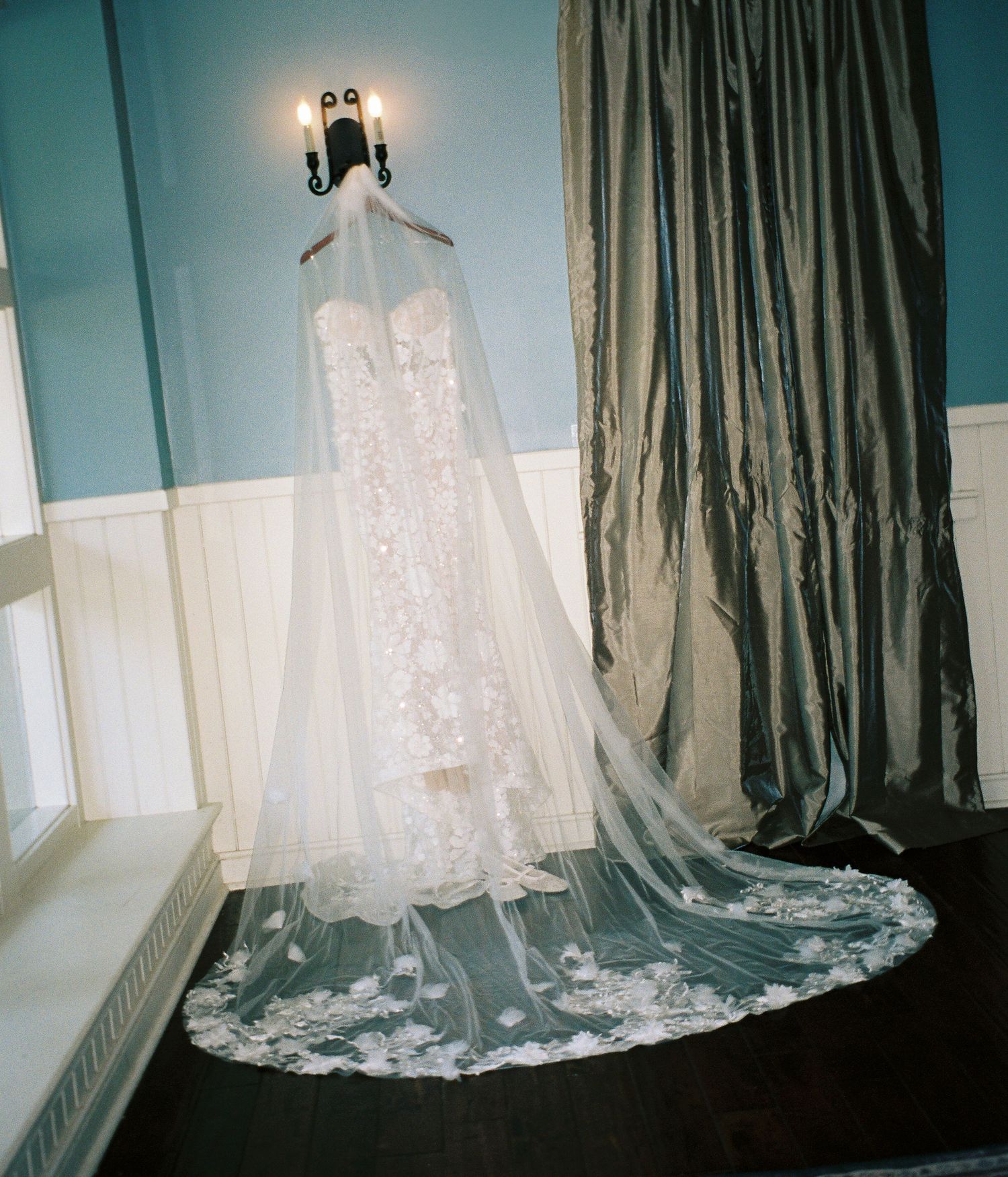 A series of elegant white wedding dresses hanging from windows with dramatic lighting and flowing fabric details.