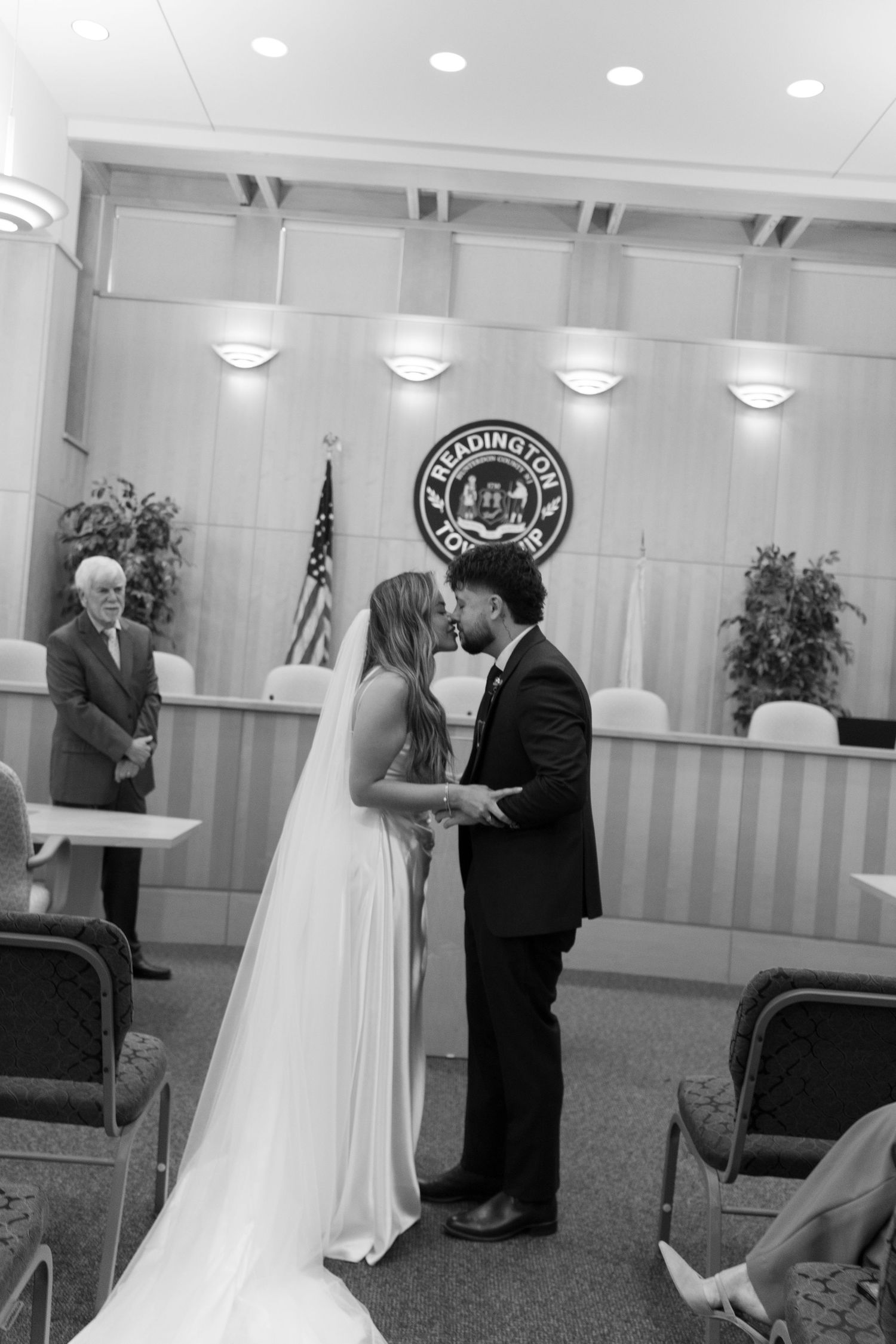 Black and white photo of bride and groom sharing first kiss at courthouse wedding ceremony.