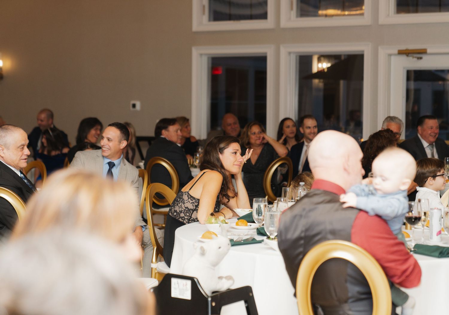 Guests seated at round tables during an indoor banquet event with white tablecloths and warm lighting.