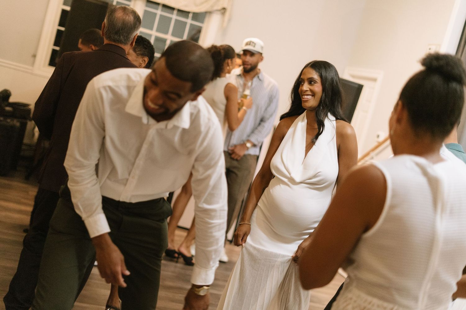 An indoor photoshoot featuring people in white attire against a decorated backdrop.