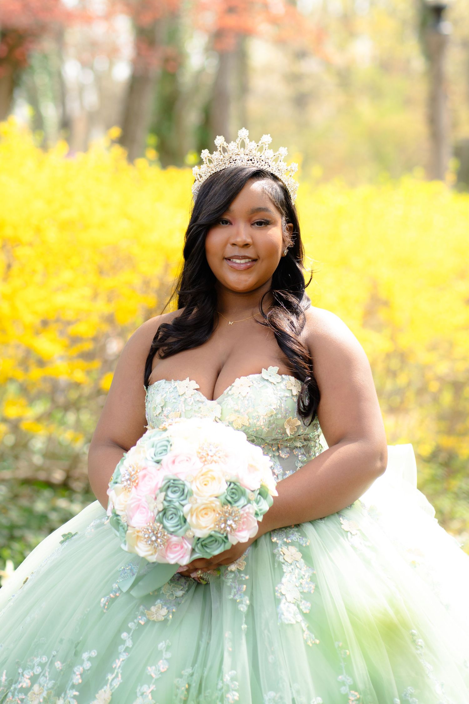 A mint green princess ballgown with floral details photographed against vibrant yellow spring foliage.