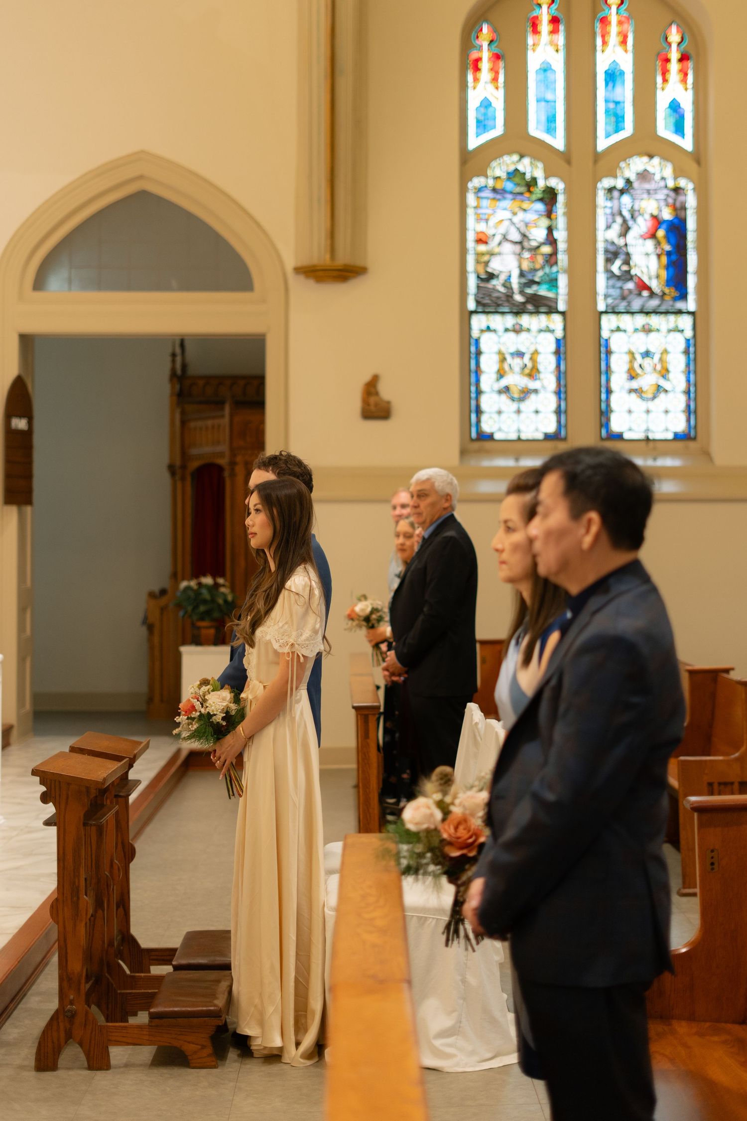 Wedding ceremony in a church with stained glass windows and elegant decor.