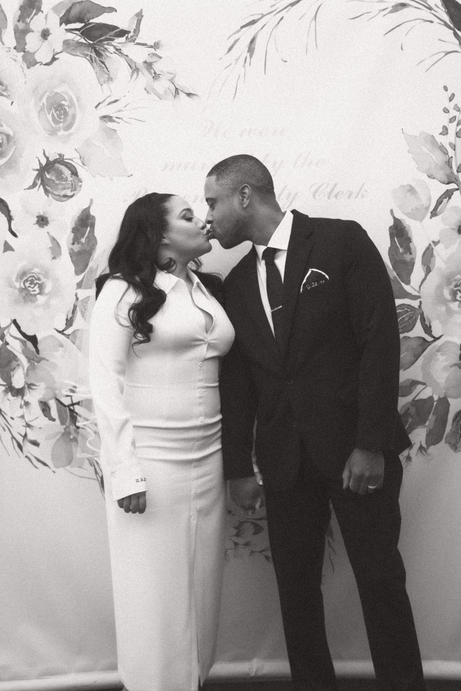 Wedding couple sharing romantic moments against floral backdrop.
