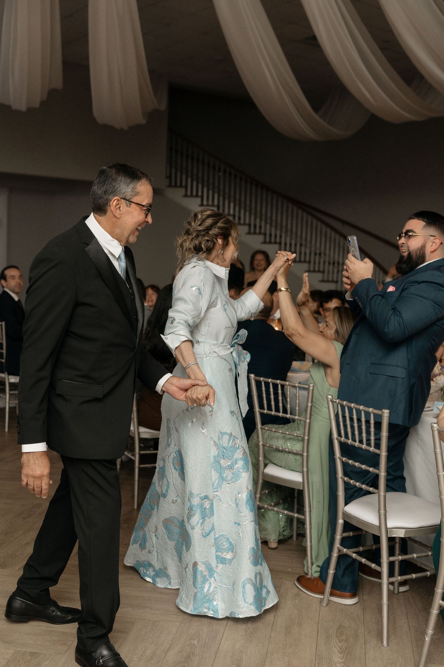 Parents of bride or groom dancing at wedding reception in elegant venue with draping.