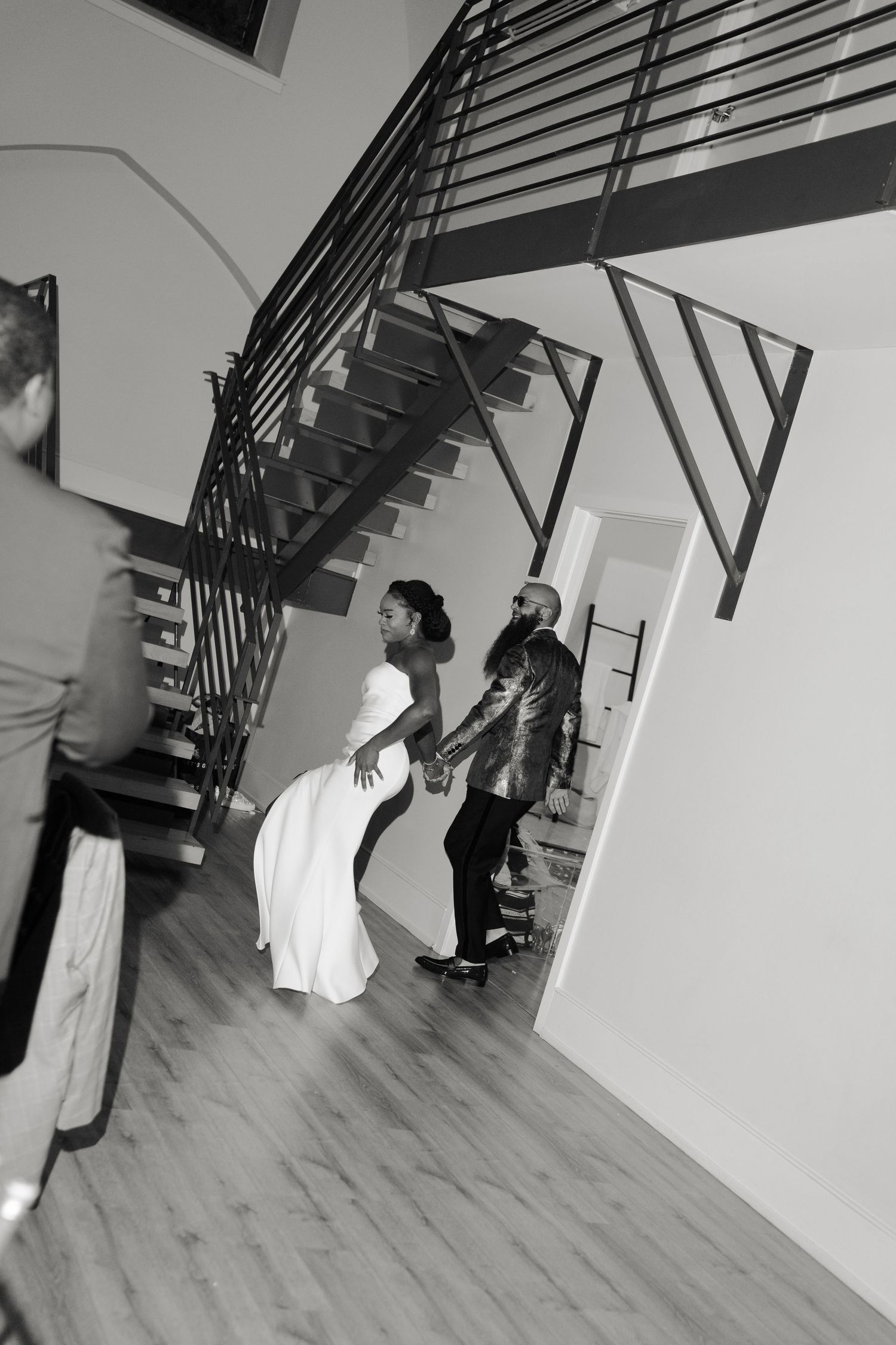 Wedding party descending modern staircase in dramatic black and white photography.