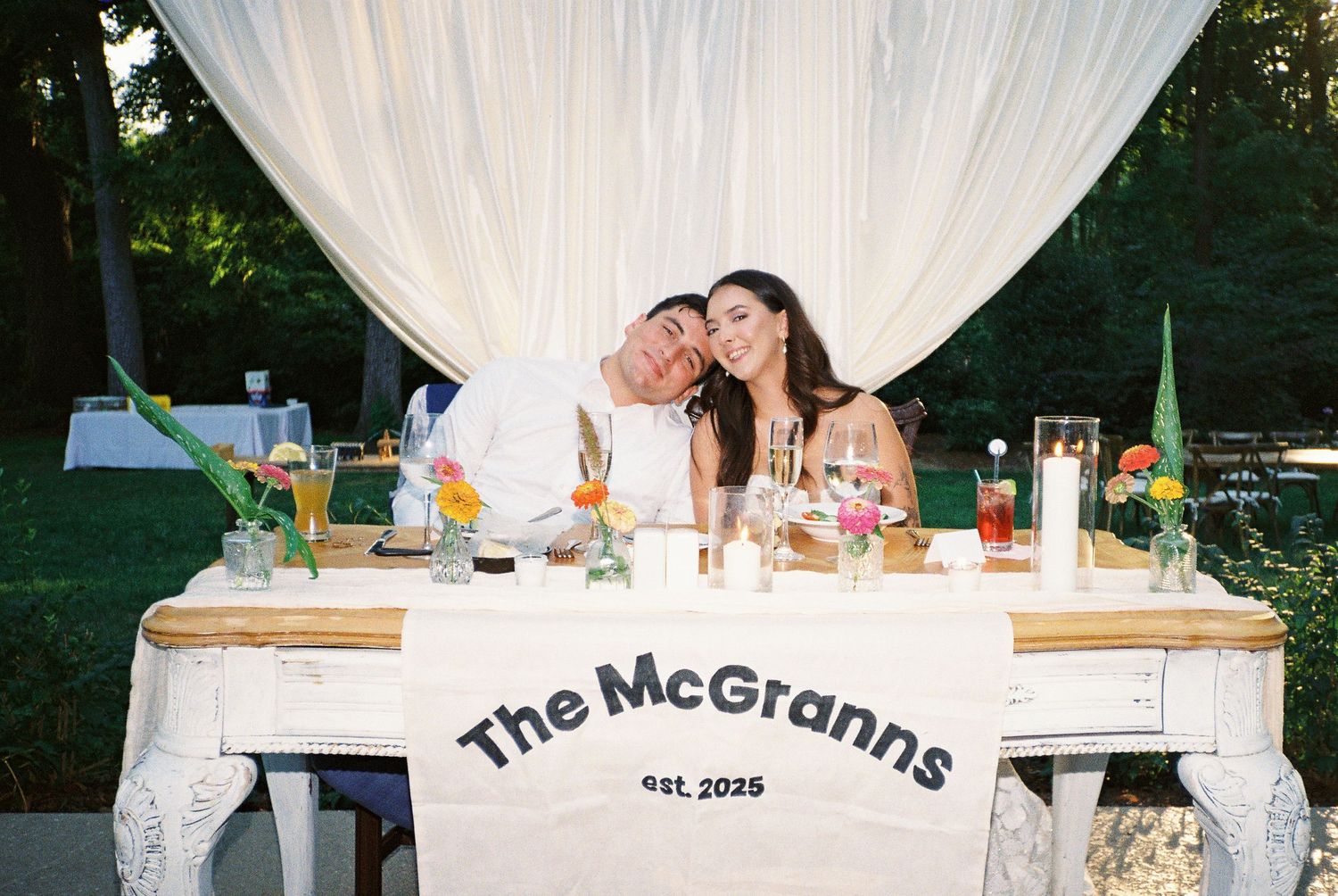 Wedding reception setup with white draping and personalized signage.