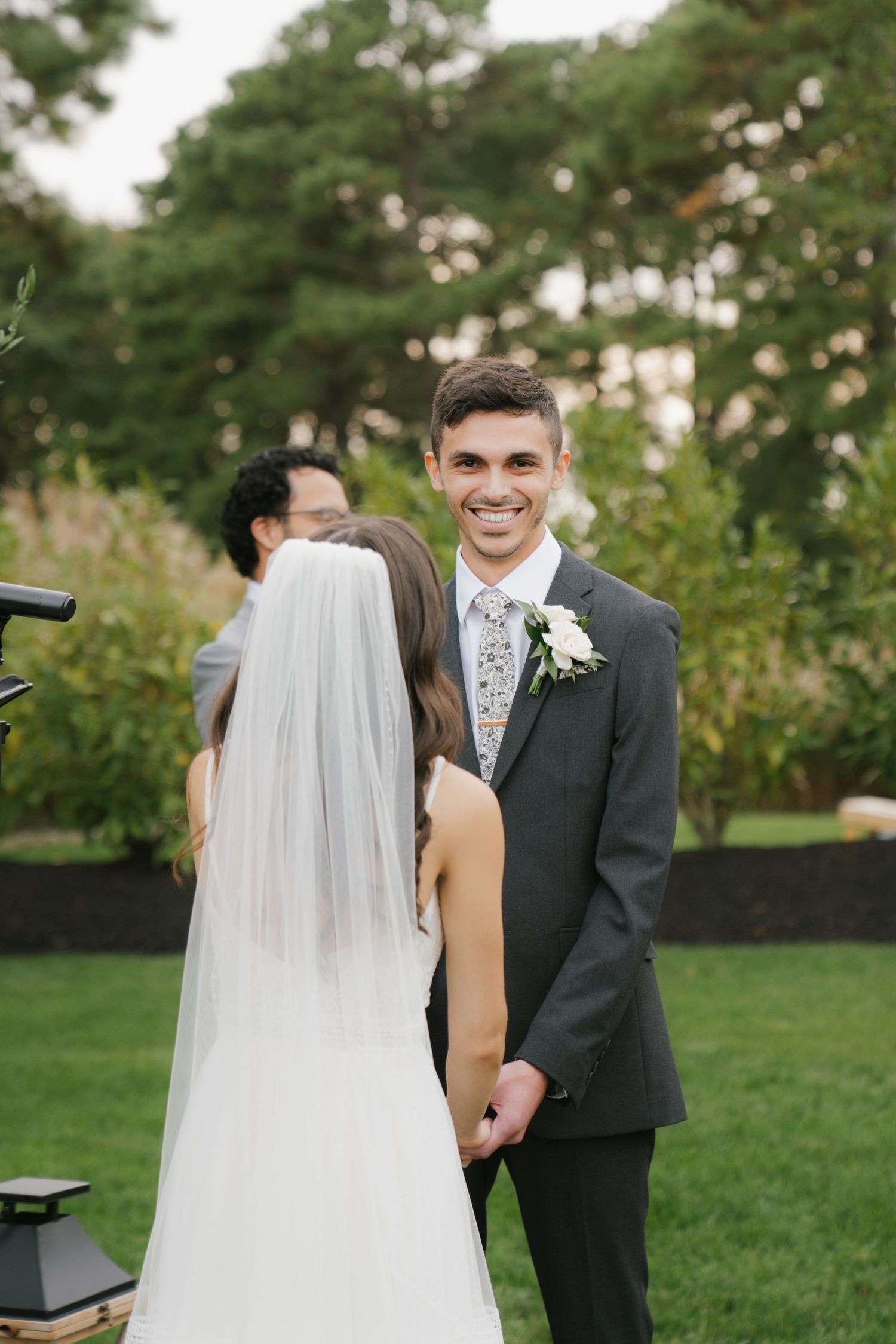 Bride and groom share a joyful moment together outdoors during their wedding photoshoot in a lush green garden setting.