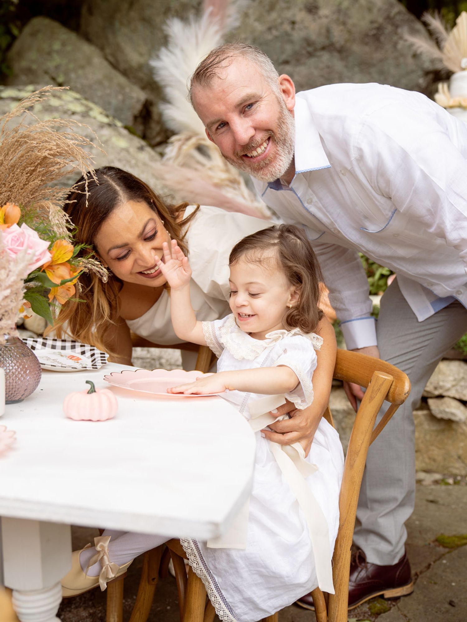 Candid outdoor photoshoot capturing joyful interactions at a white-themed celebration.