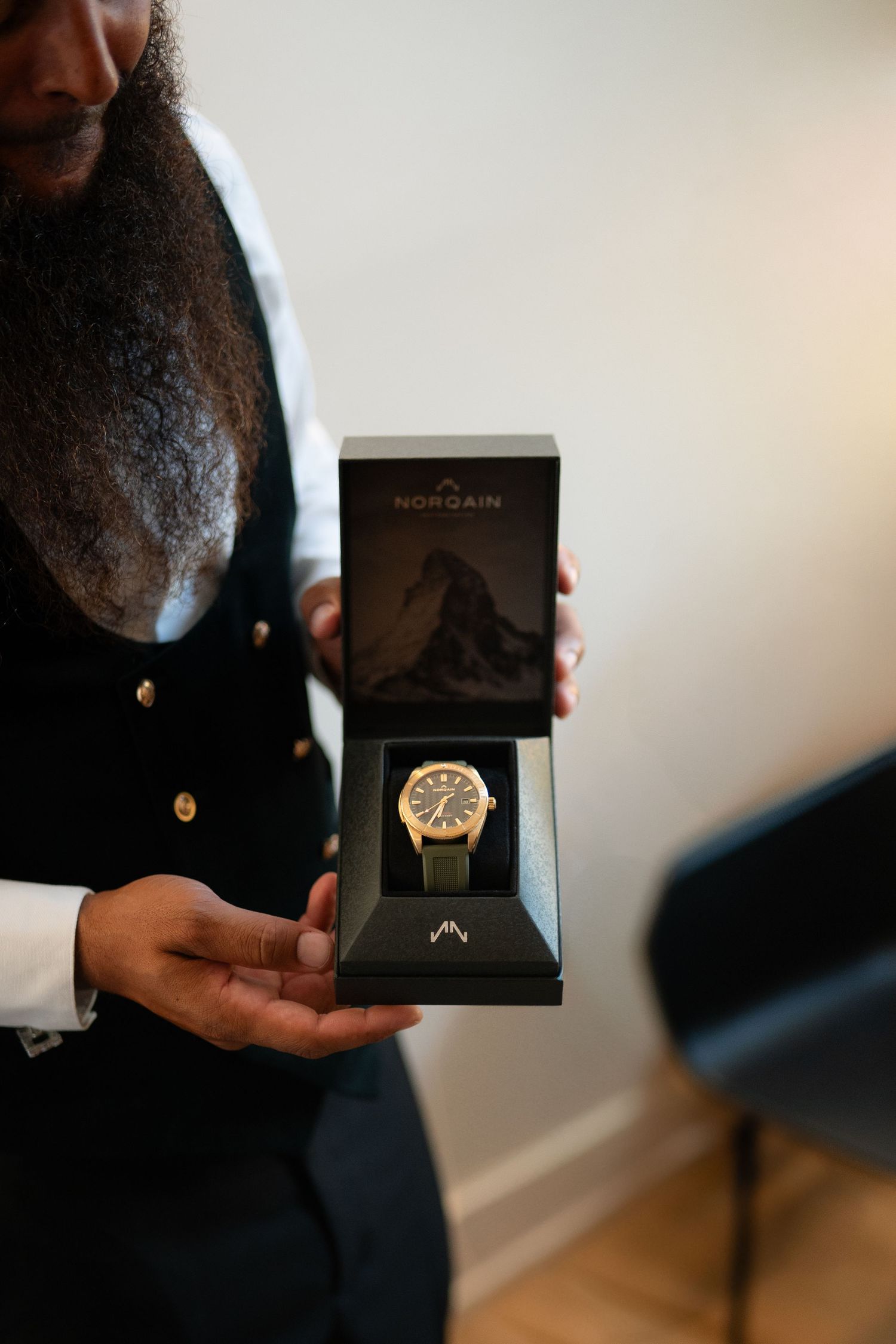 Close-up shot of hands holding an open luxury watch box displaying a gold timepiece.
