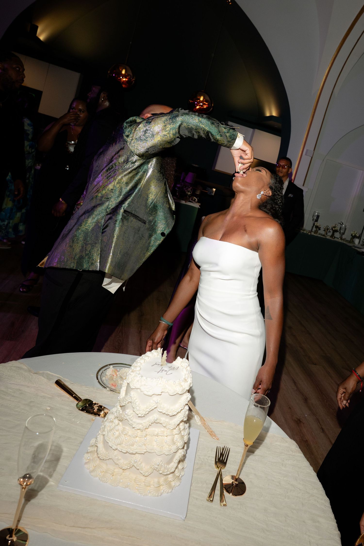 Wedding celebration with guests gathered around the cake table during reception.