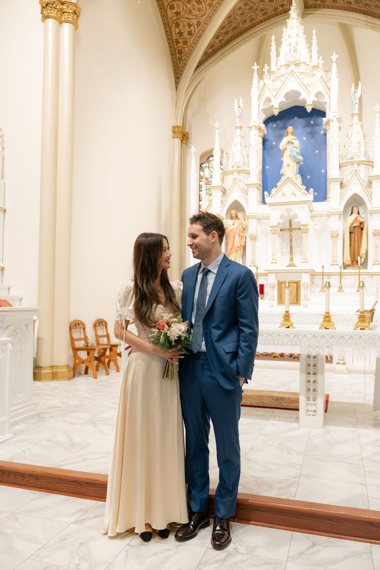Intimate wedding ceremony in a church with cream walls and ornate Gothic details.