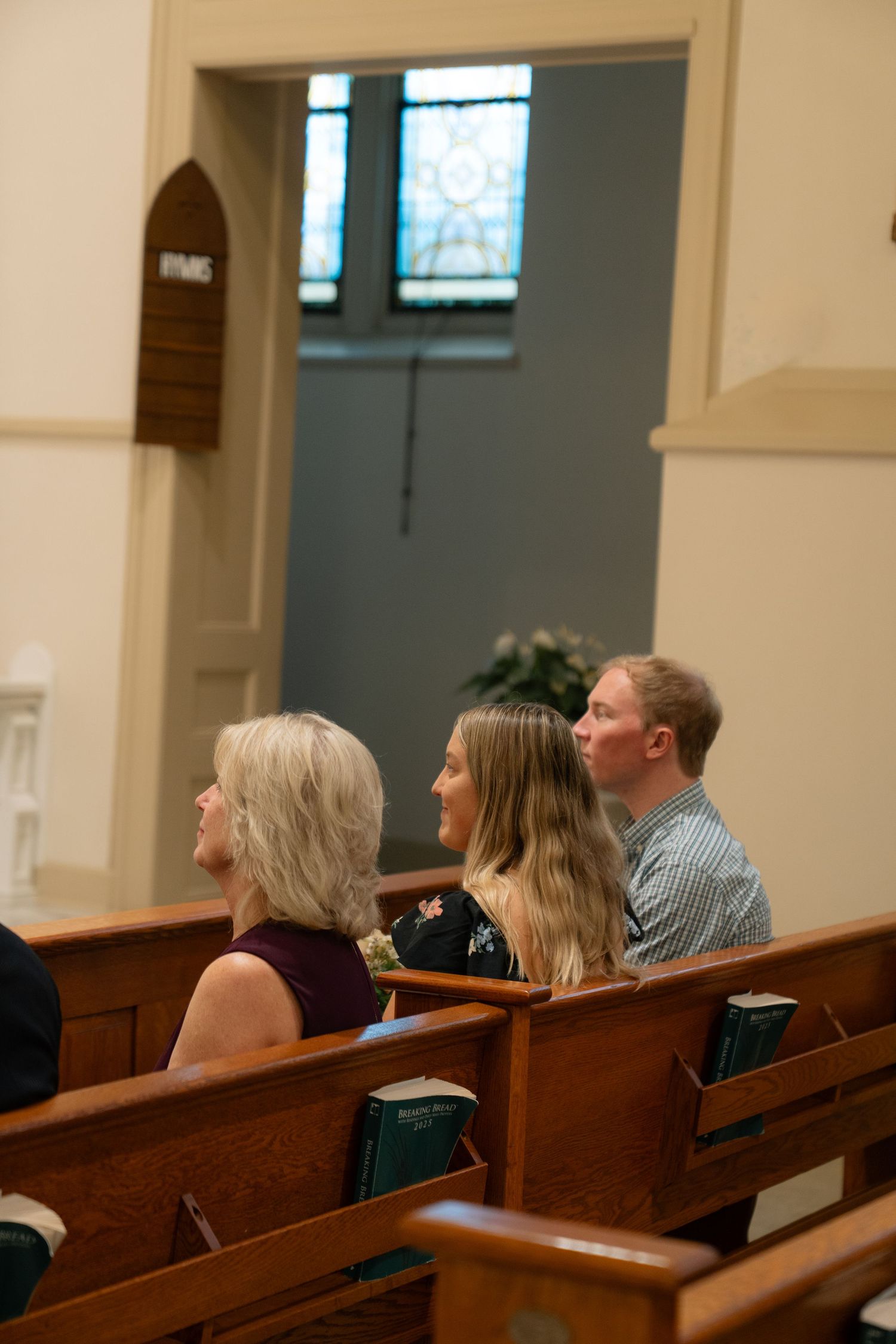 Wedding guests seated in wooden pews inside a traditional church sanctuary.