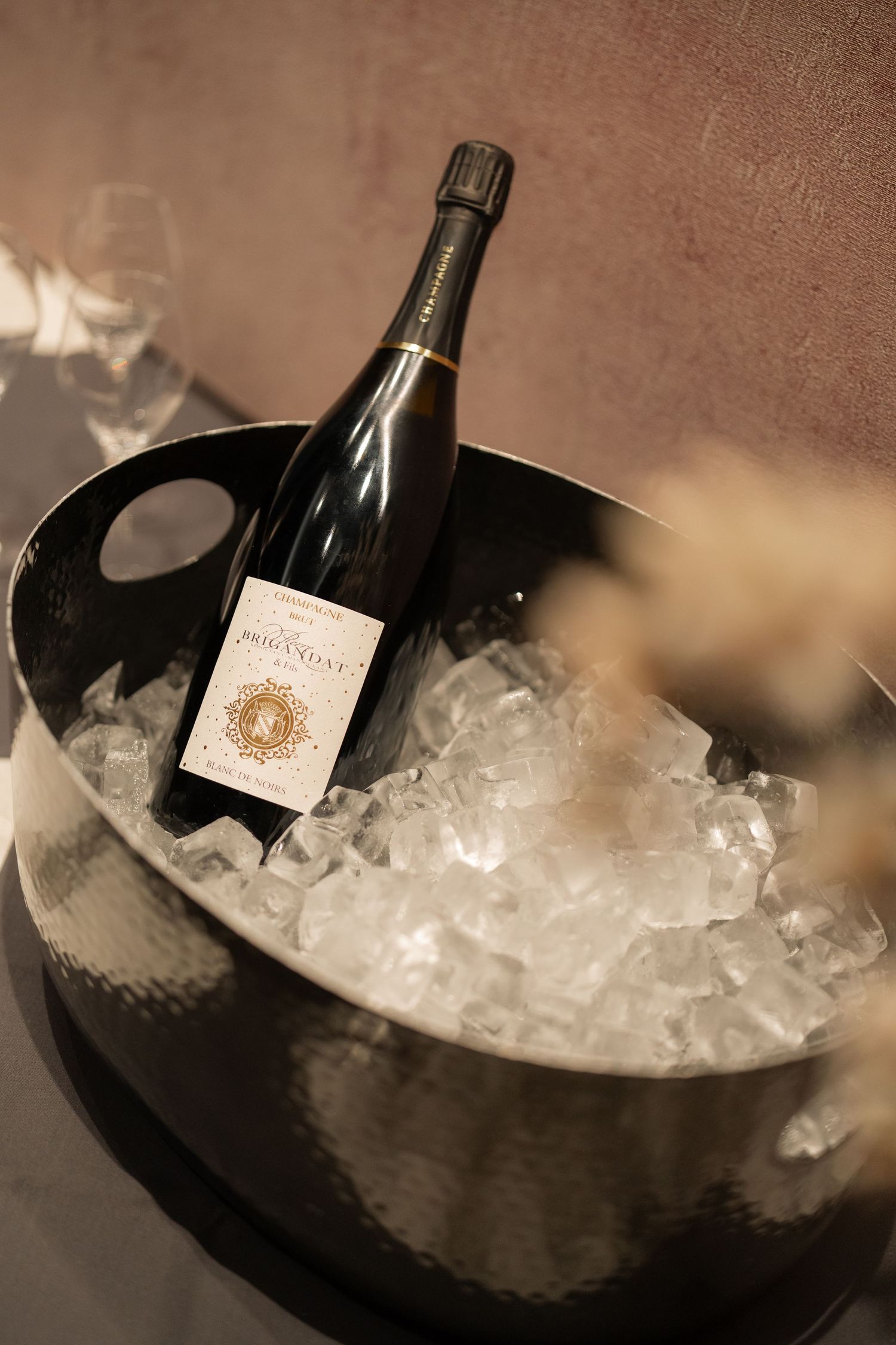 Champagne bottle chilling in black ice bucket with crushed ice at luxury event.