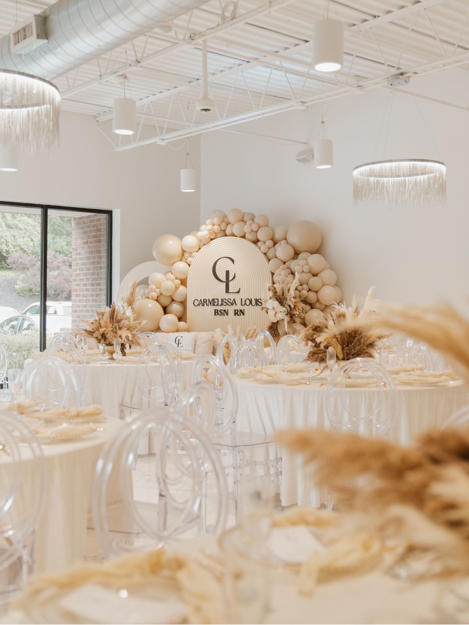 Elegant white and gold event space with balloon arrangements and crystal chandeliers.