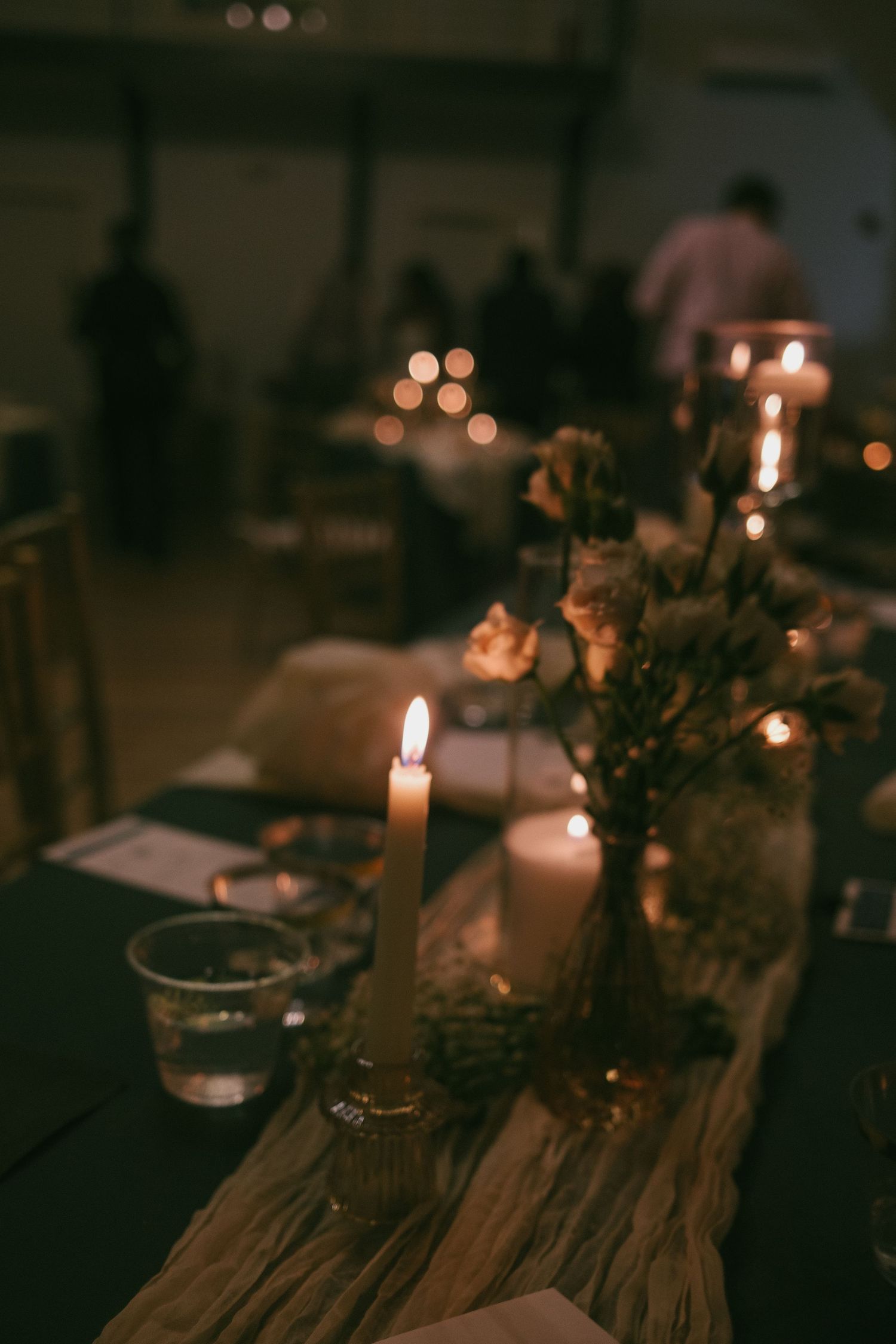 Candlelit table setting with rustic wooden decor and soft bokeh lighting creates an intimate atmosphere.