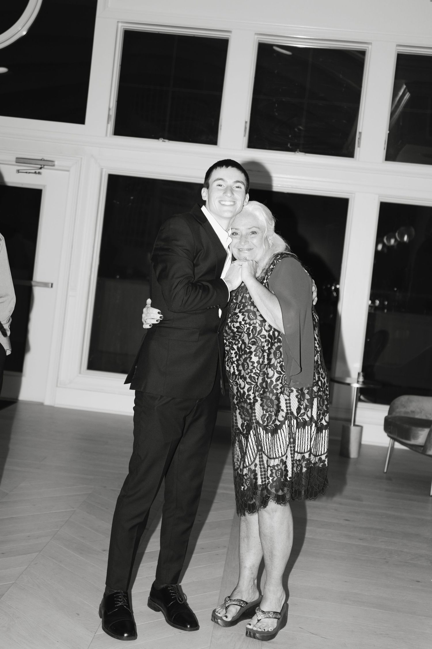A couple dances together on a wooden floor in formal attire during what appears to be a ballroom dance event.