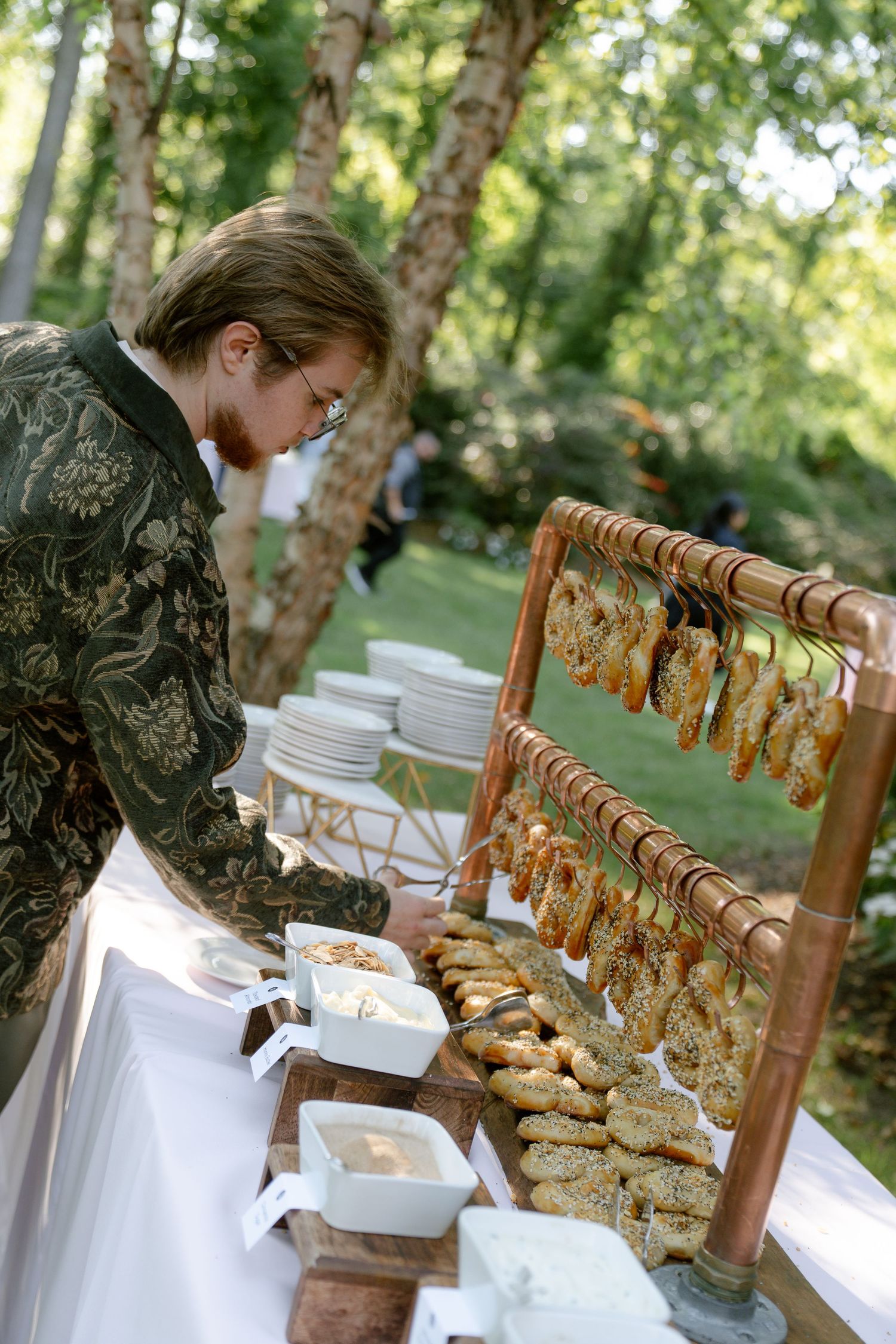 Rustic outdoor buffet table setup with wooden chairs and white linens in a garden setting.