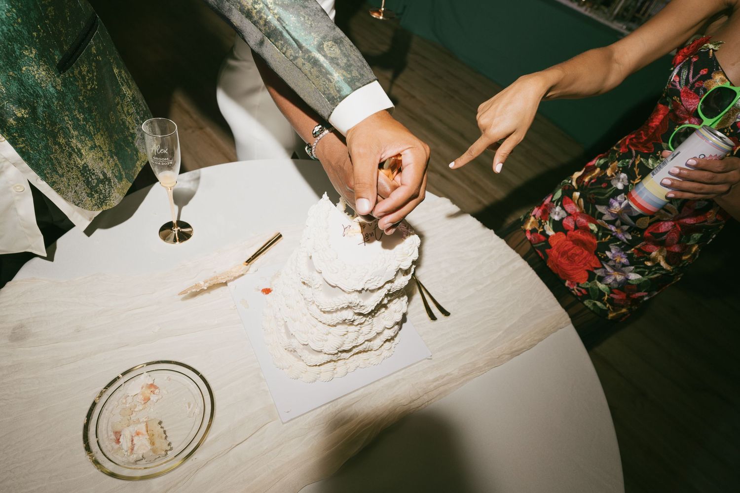 Close-up view of hands cutting into a white wedding cake during reception.
