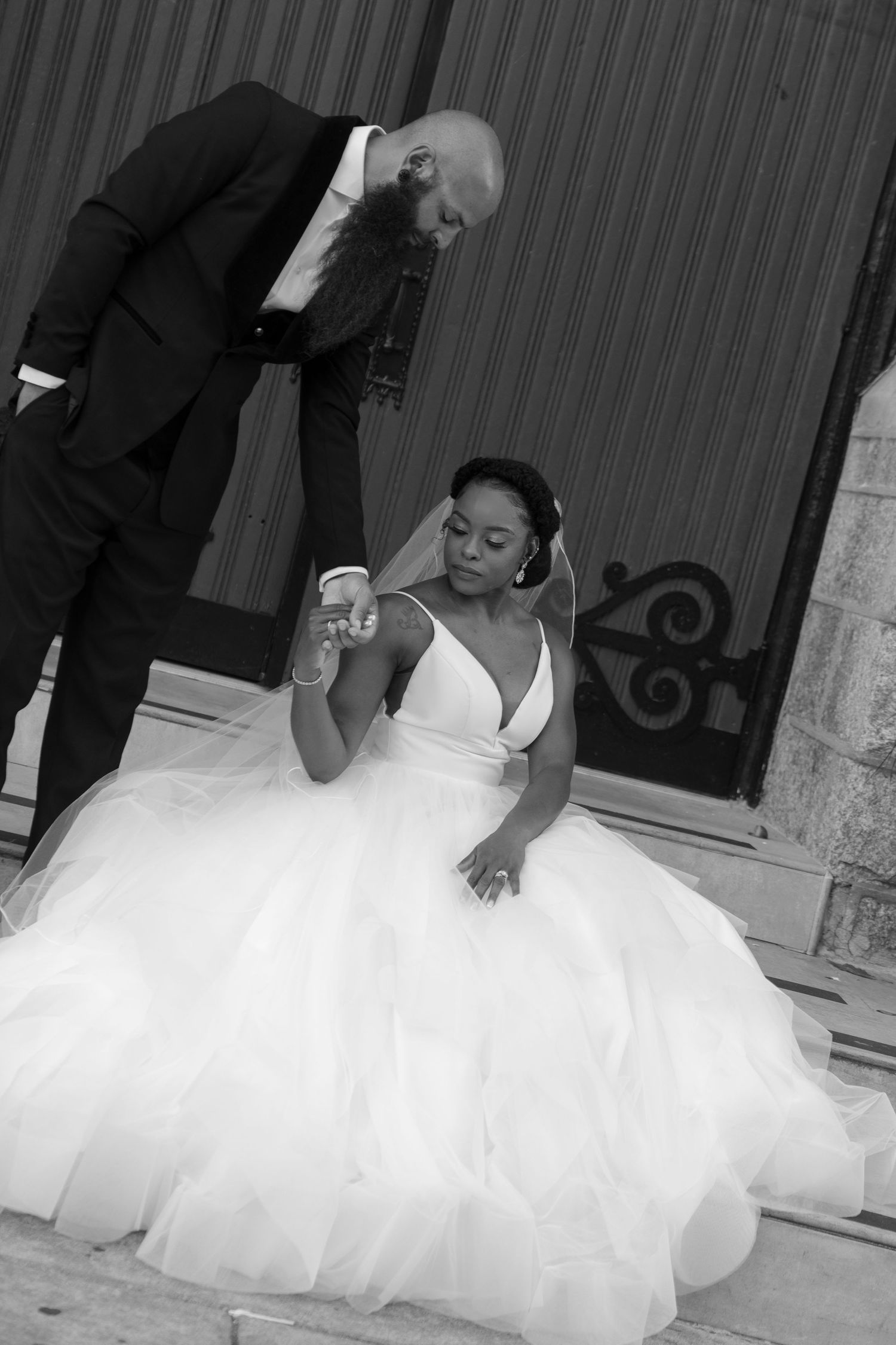 Black and white wedding photos showing playful moments against church architecture.