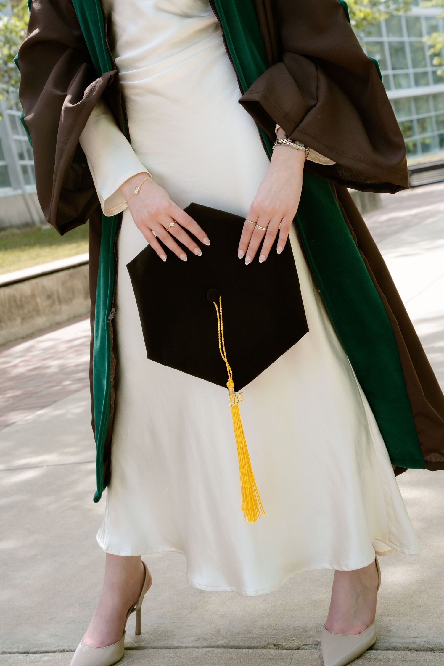 Close-up of graduation attire showing cap with tassel and green academic stole.