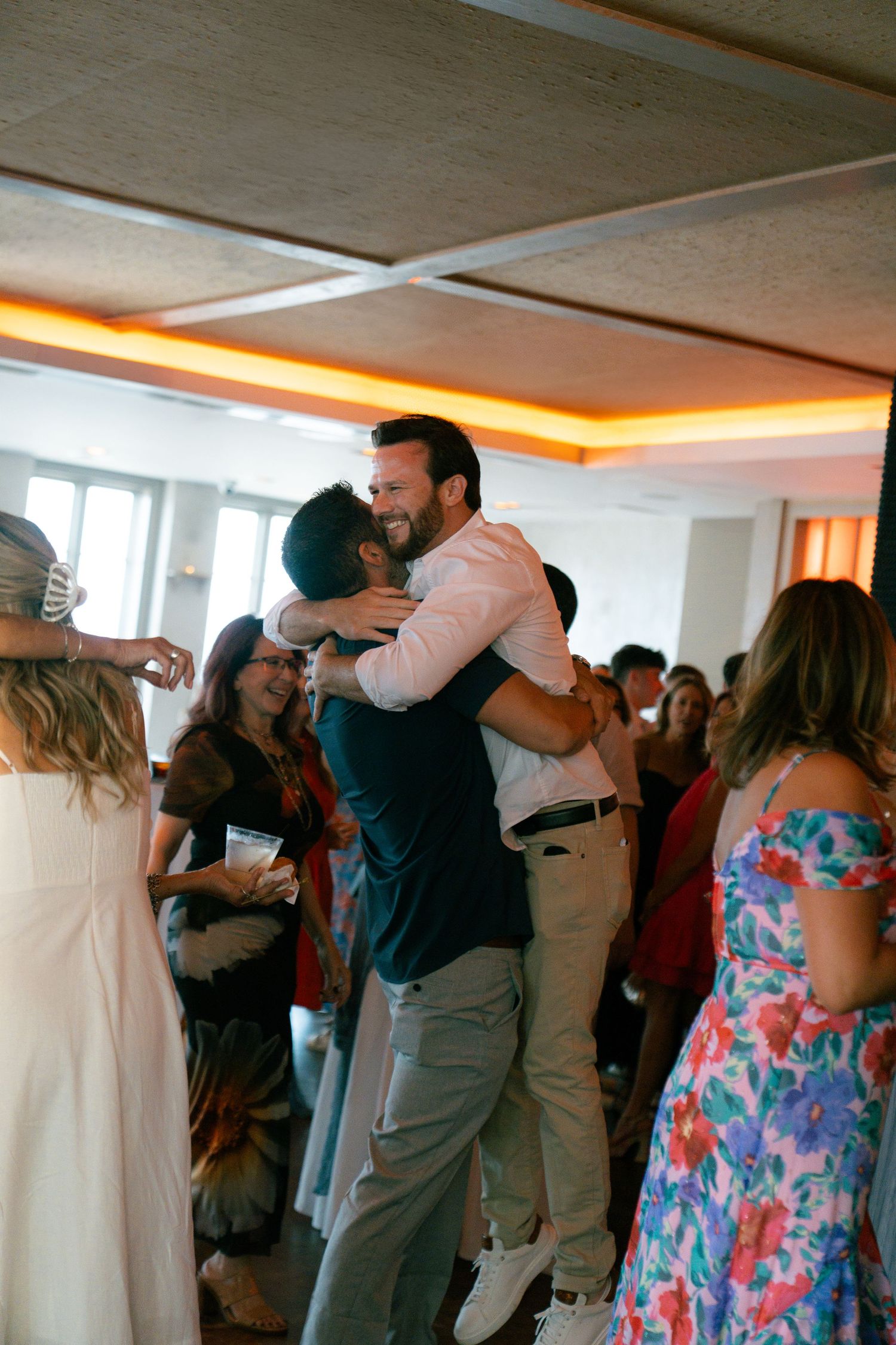 Wedding guests dancing and celebrating in an indoor reception space.