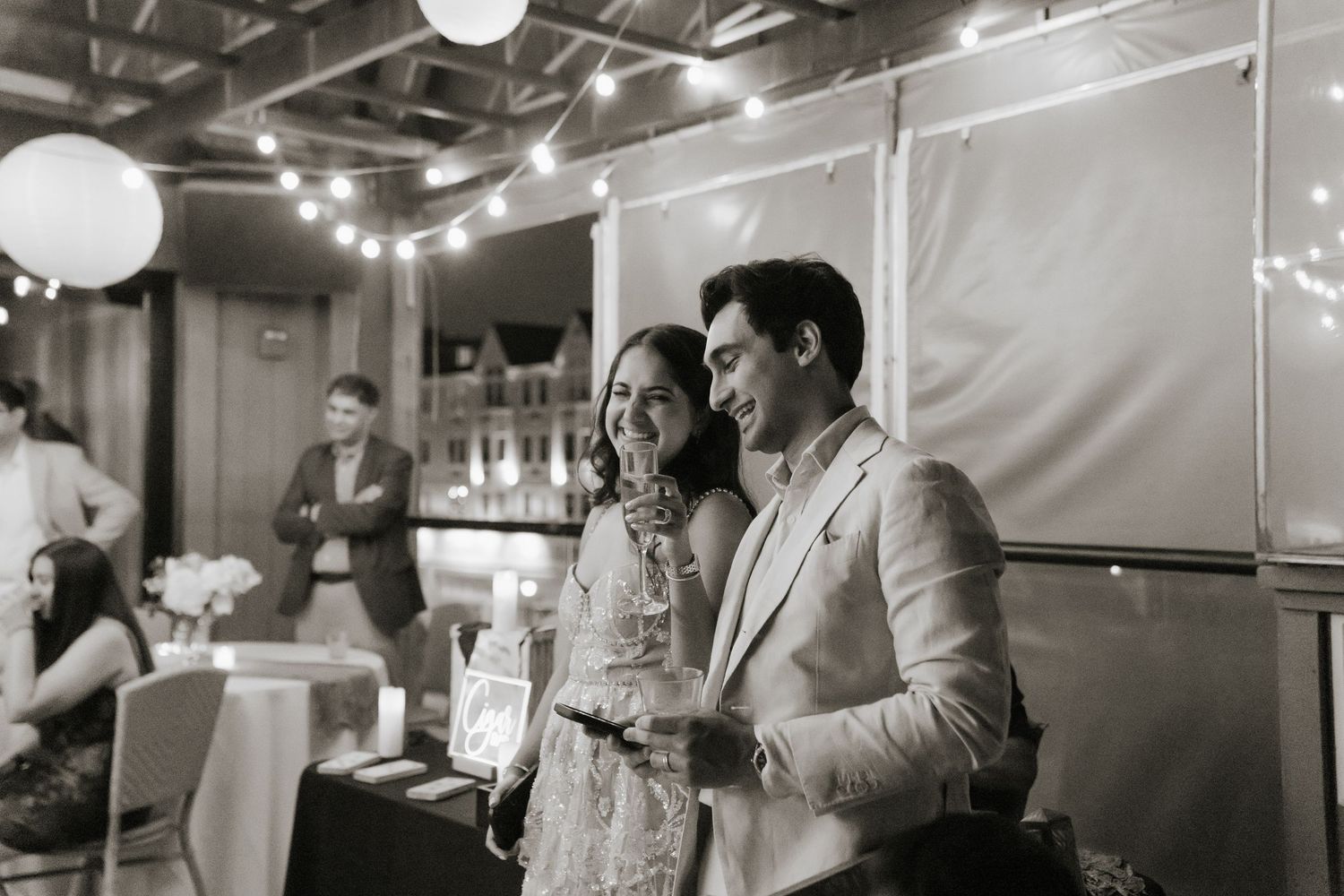 Black and white candid shots of guests mingling and socializing at an indoor celebration.