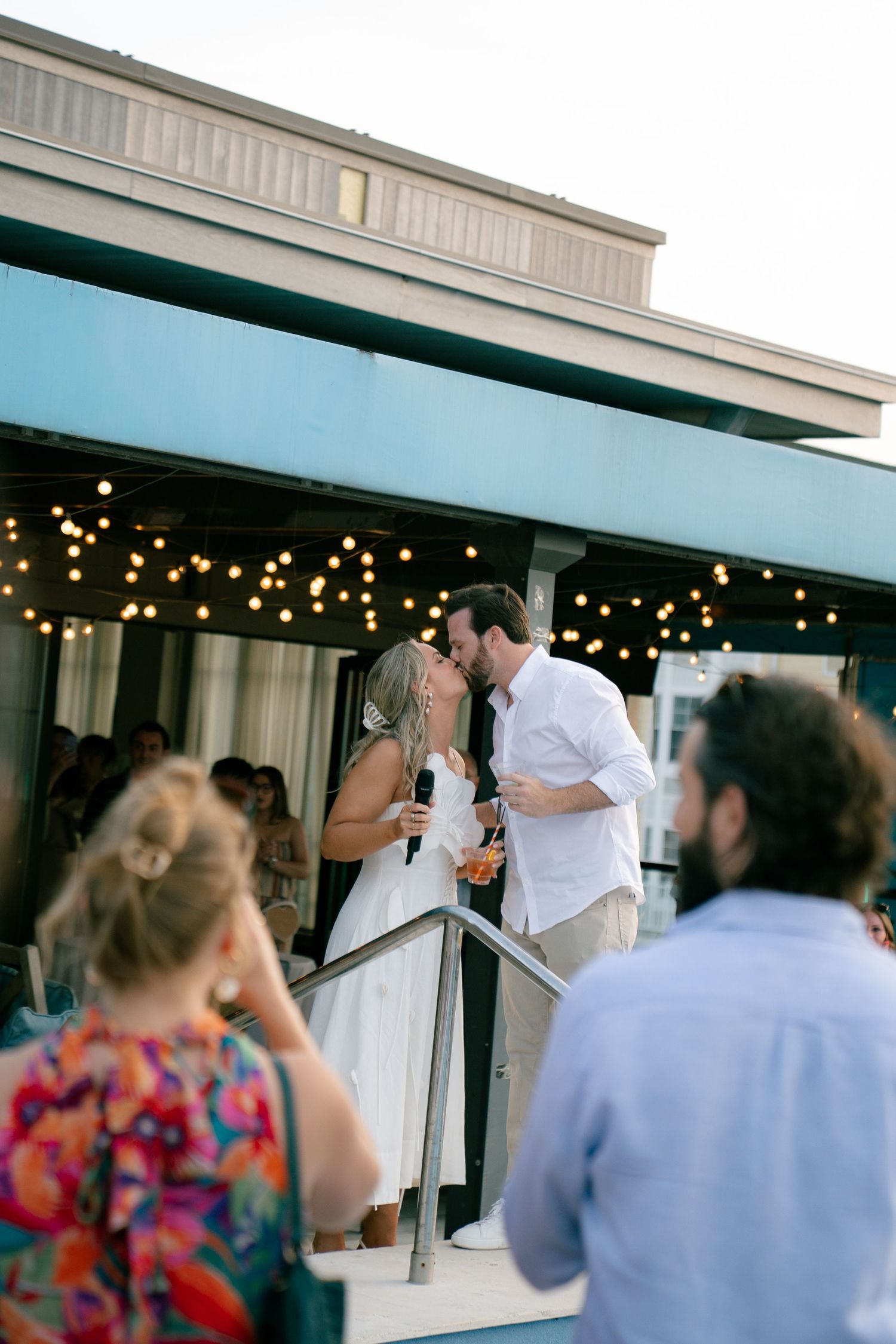 Couple sharing a romantic moment on outdoor steps with string lights in background.