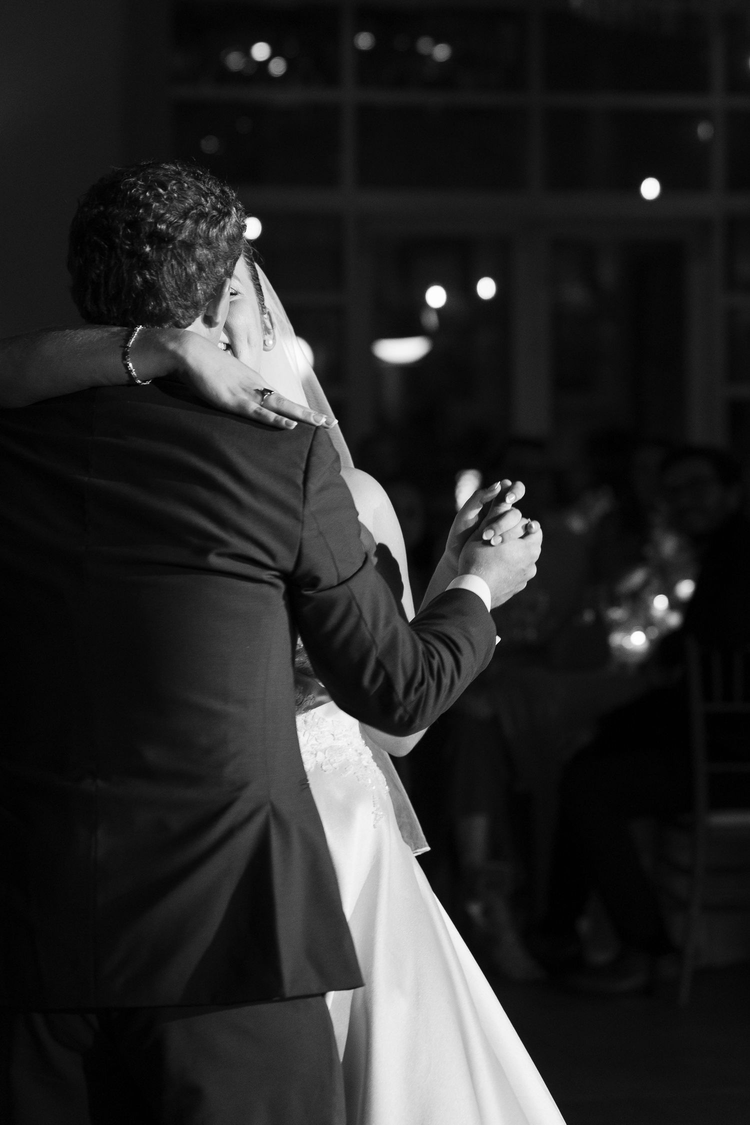 Bride and groom sharing their first dance in a romantic black and white wedding reception photo.