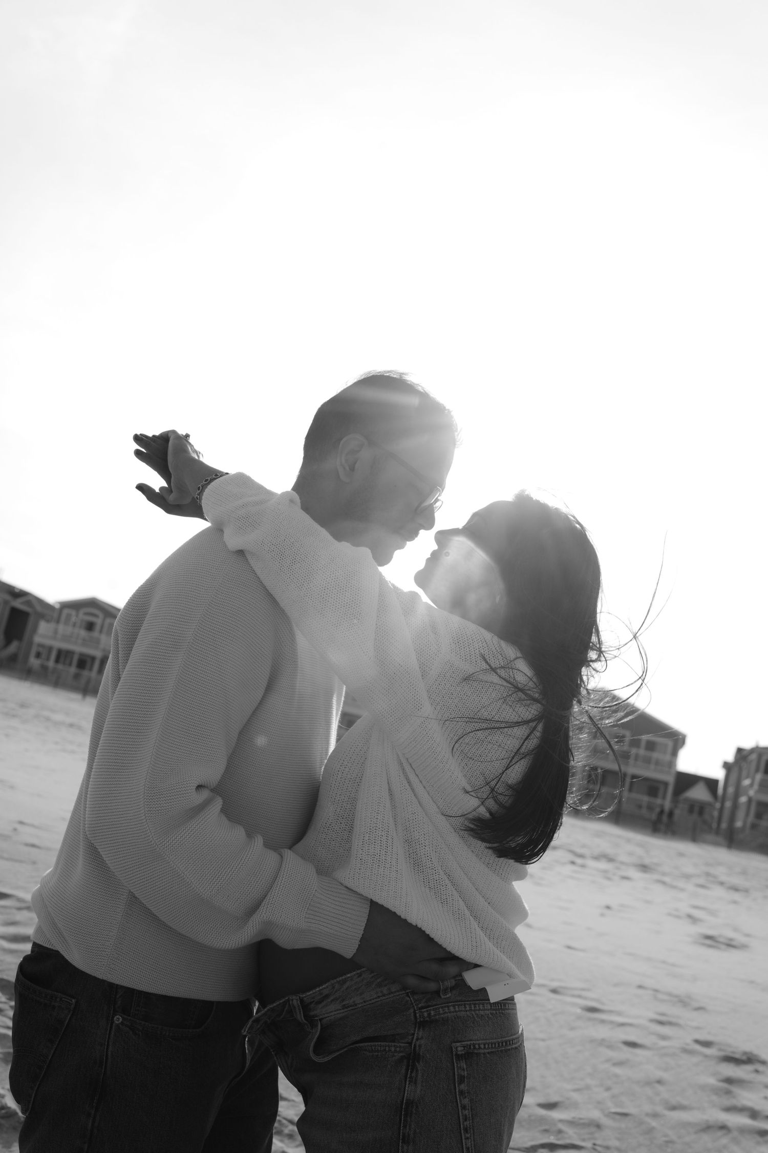 A black and white triptych shows a couple sitting together on a beach, captured from behind at different angles.
