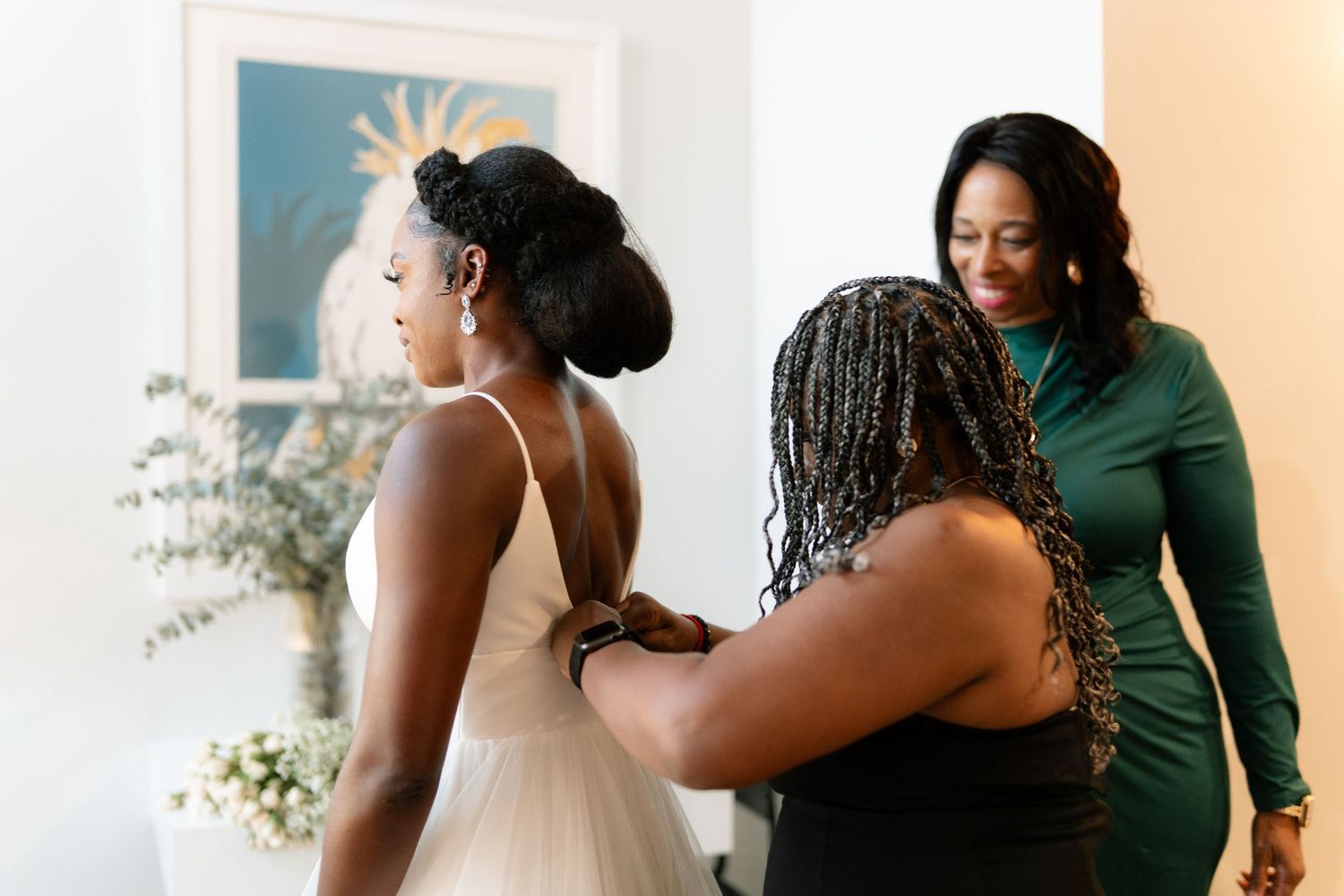 Wedding dress preparation scene with attendants helping with final adjustments.