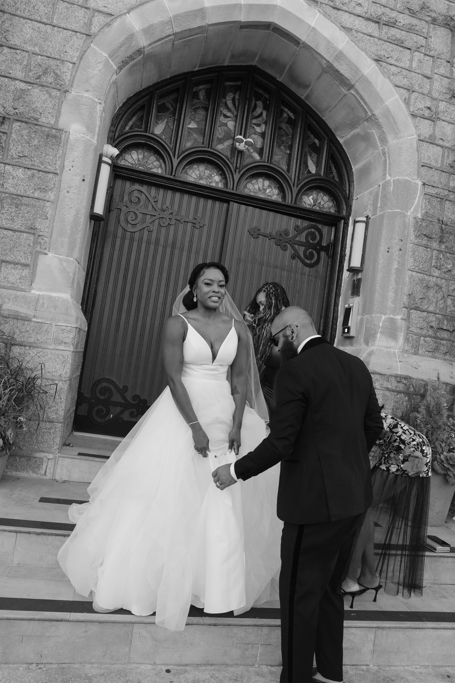 Black and white photo of couple sharing tender moment on church steps during wedding.