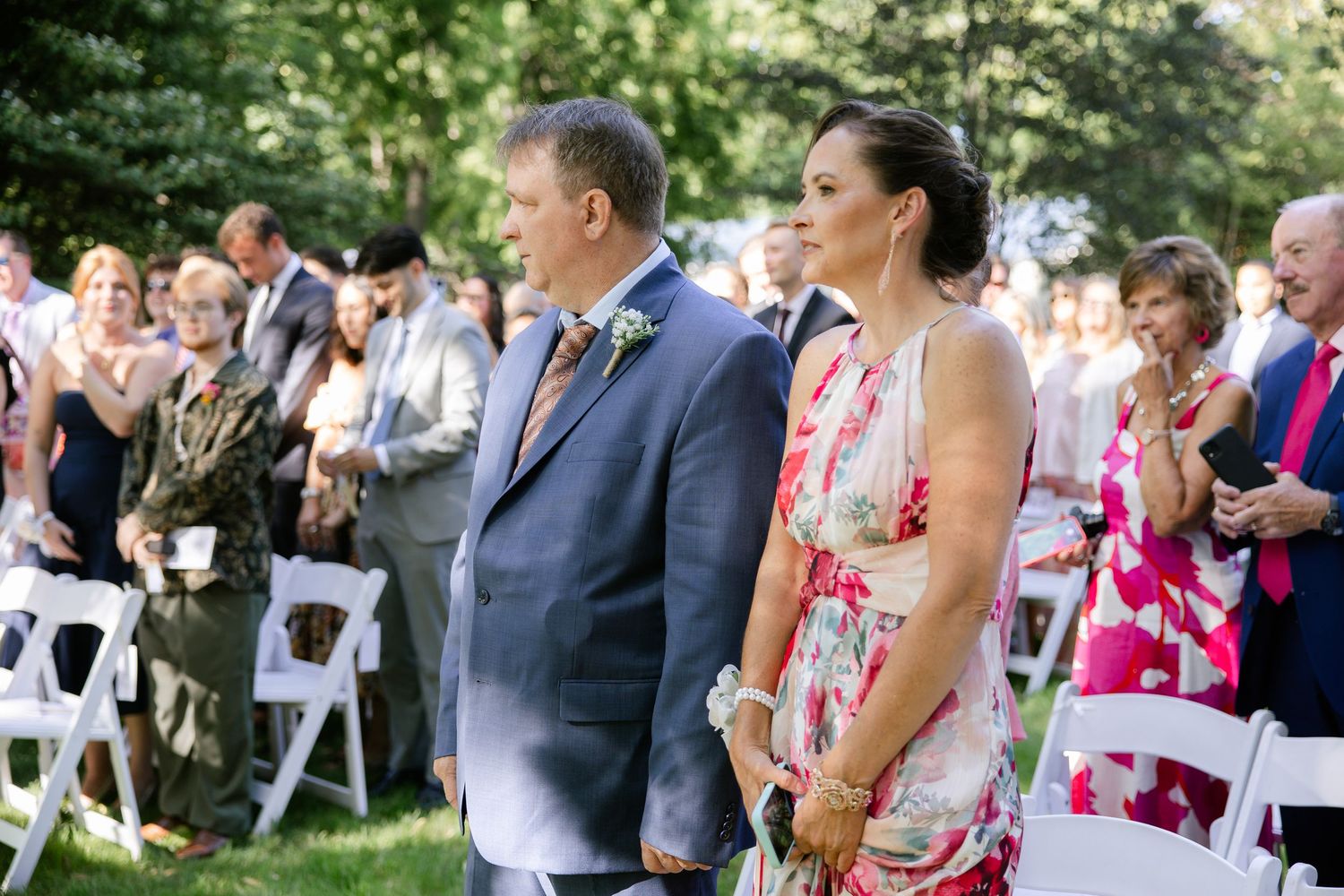 Wedding guests mingle and celebrate during an outdoor garden reception on a sunny afternoon.