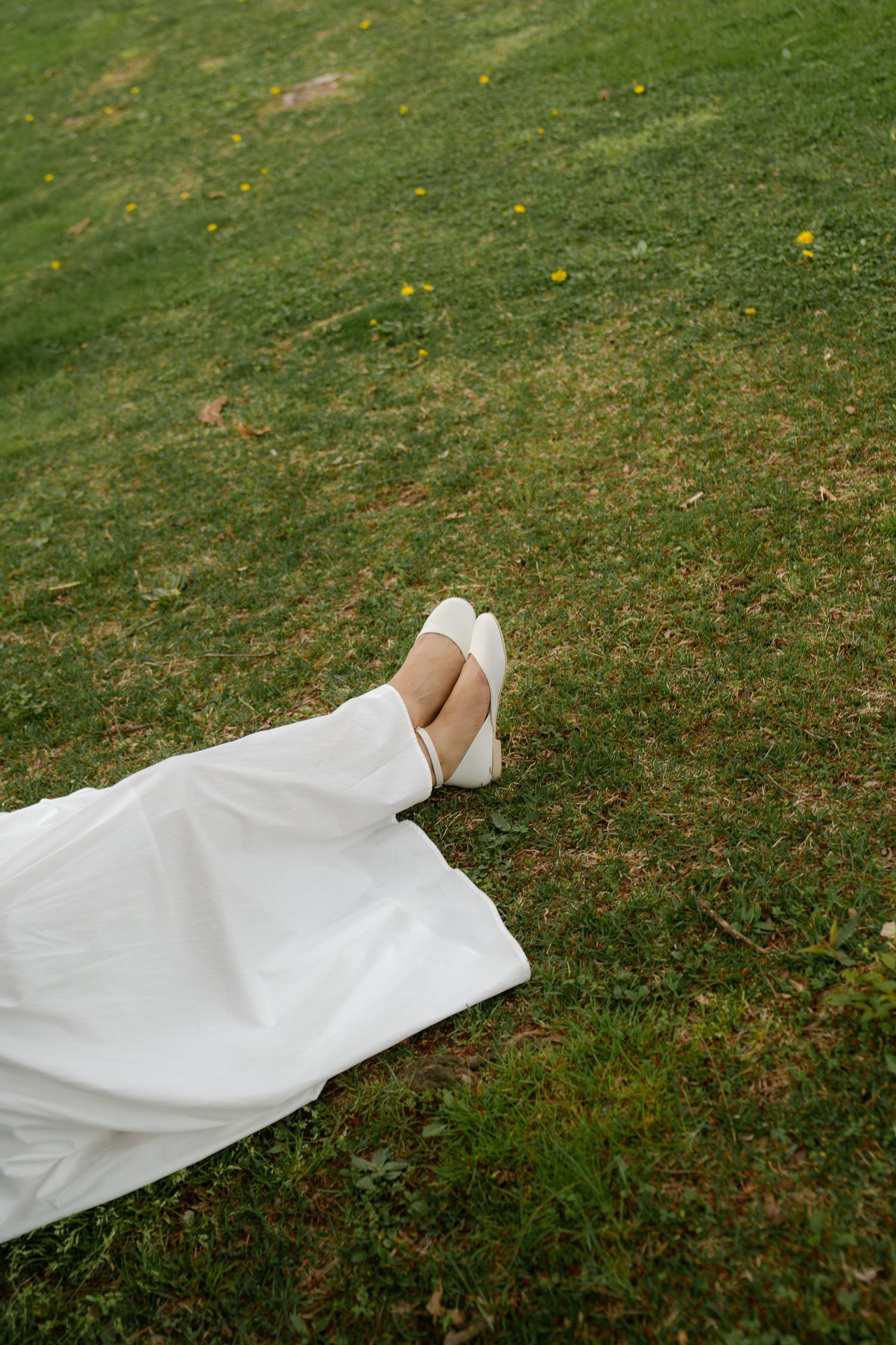 White wedding dress fabric flowing over green grass in an artistic composition.
