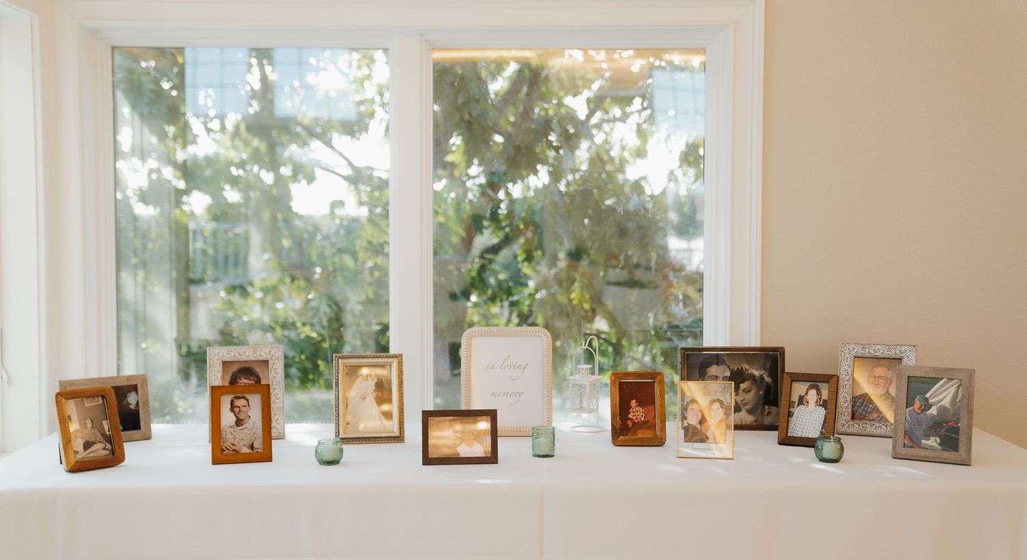 A gallery wall displays multiple framed artworks and photographs along a beige wall with windows letting in natural light.