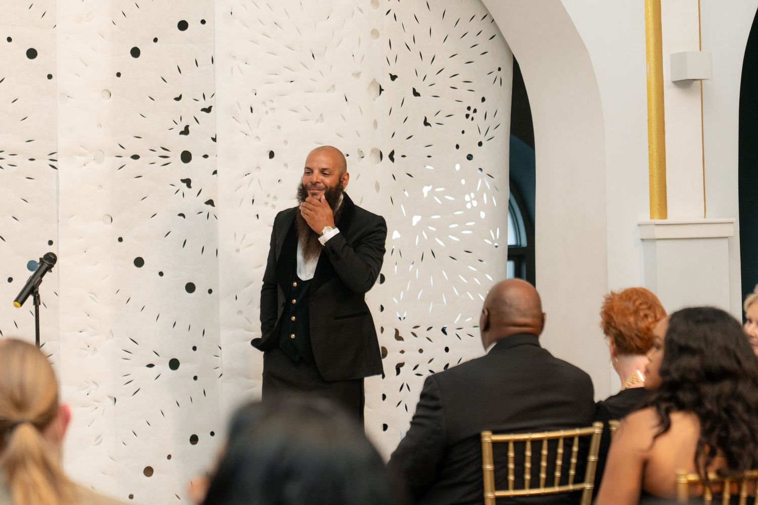 Wedding celebration in a modern venue with white walls decorated with artistic black dot patterns.