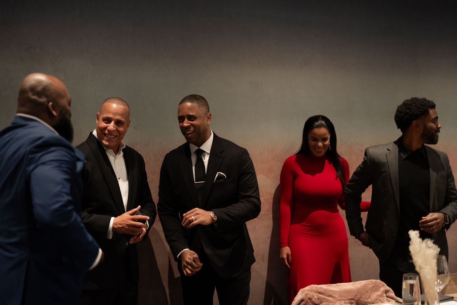 Group of people in formal attire interacting at an indoor event.