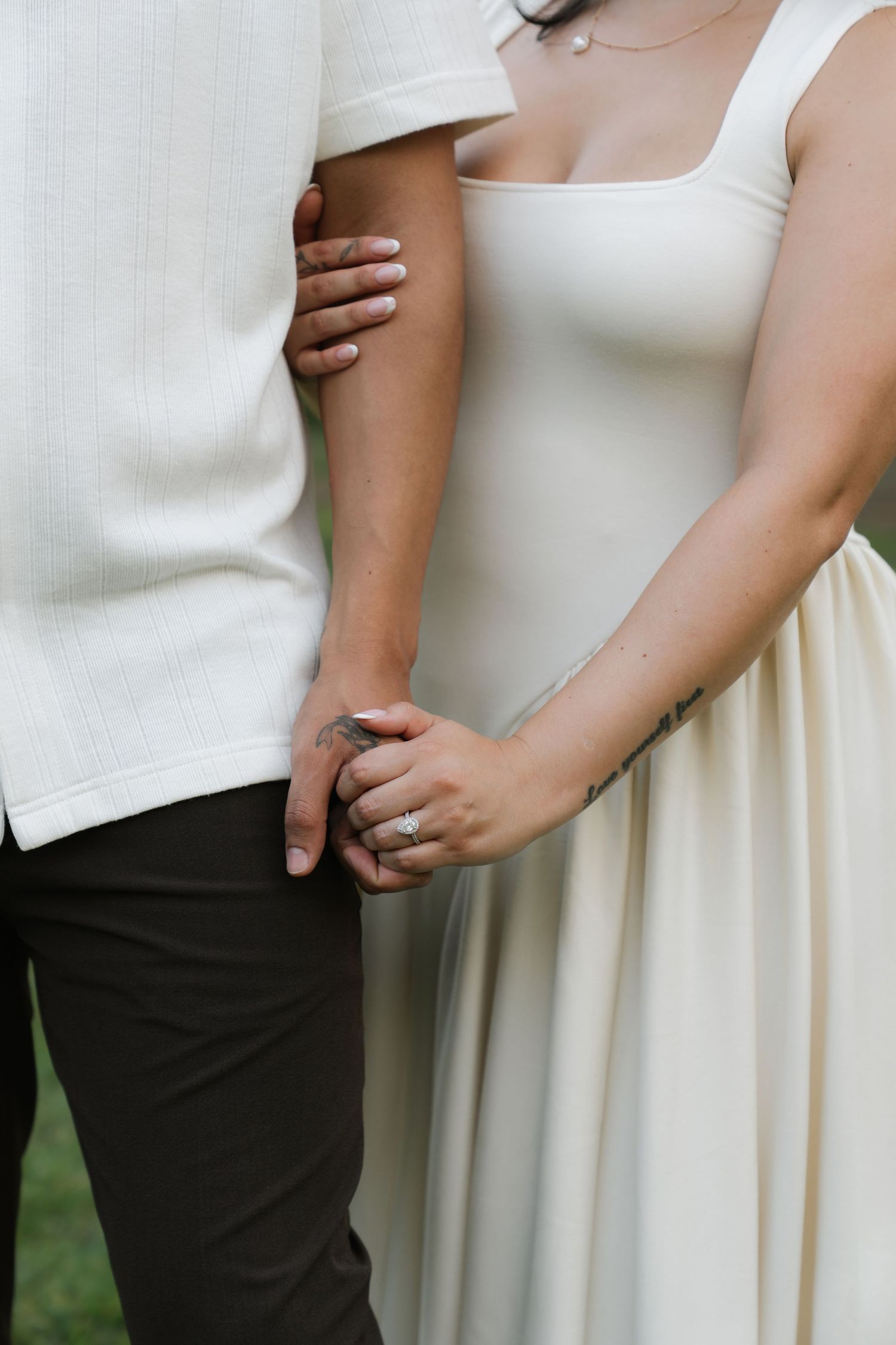 Close-up details of white wedding attire and gentle embrace.