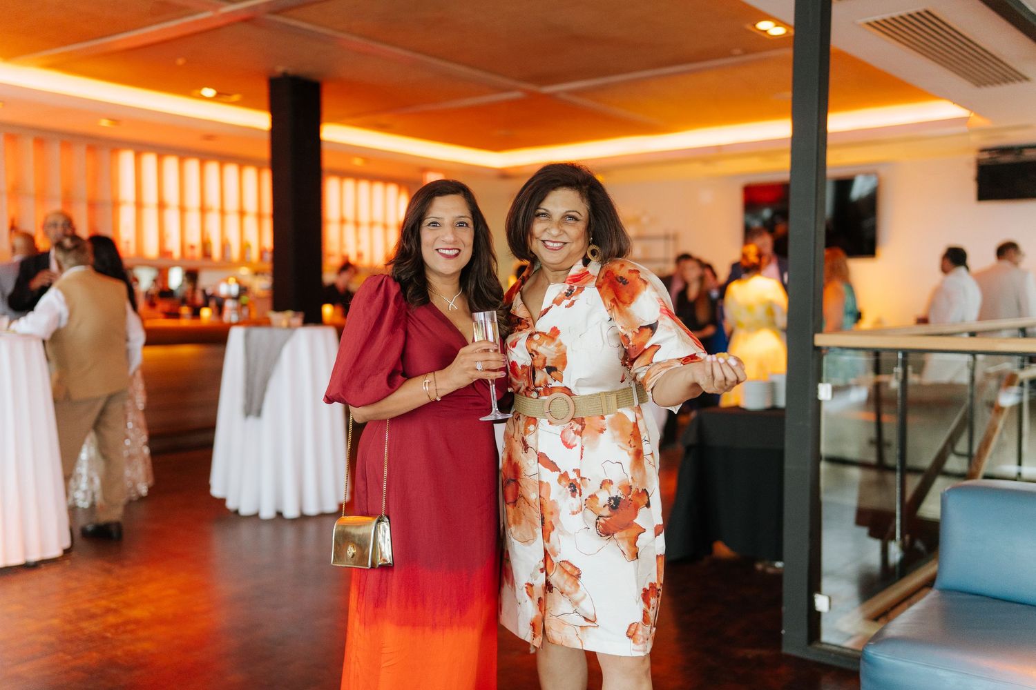 Indoor reception venue decorated with warm orange lighting and white table settings.
