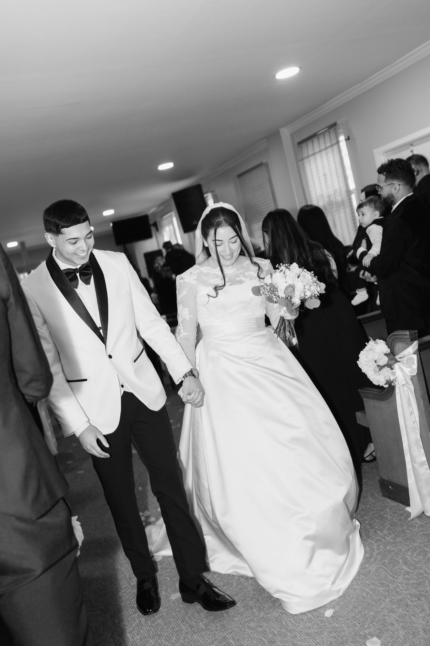 Black and white wedding reception photo showing bride in white gown dancing with guests in formal attire.