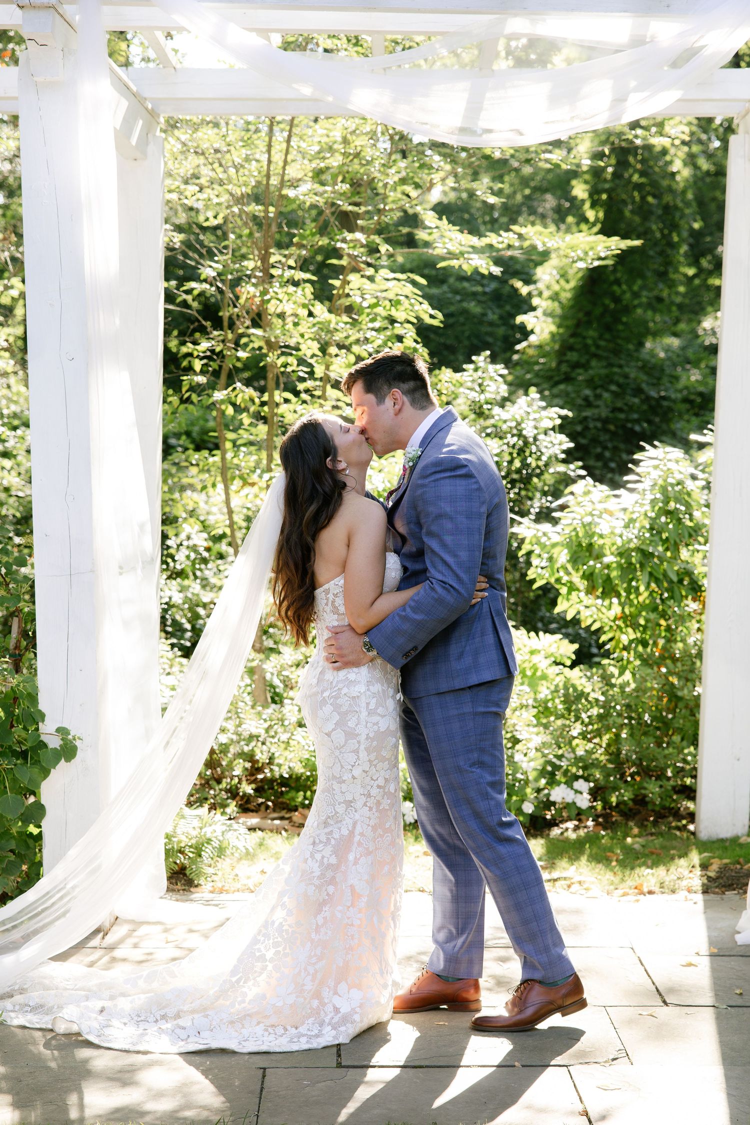 Romantic wedding photos captured under an elegant white pergola on a sunny summer day.