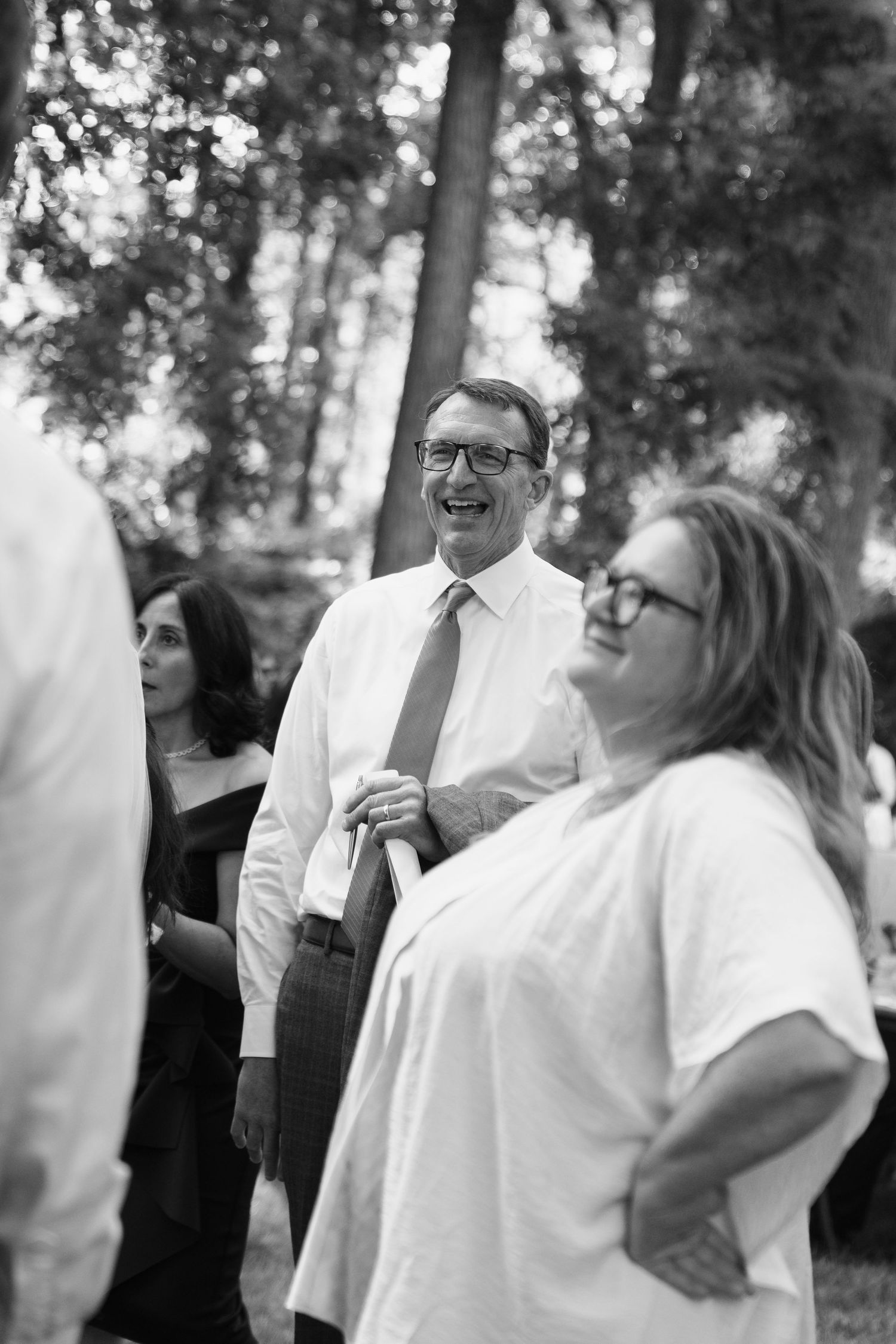 A candid black and white photo sequence shows joyful laughter and interaction between people at an outdoor event.