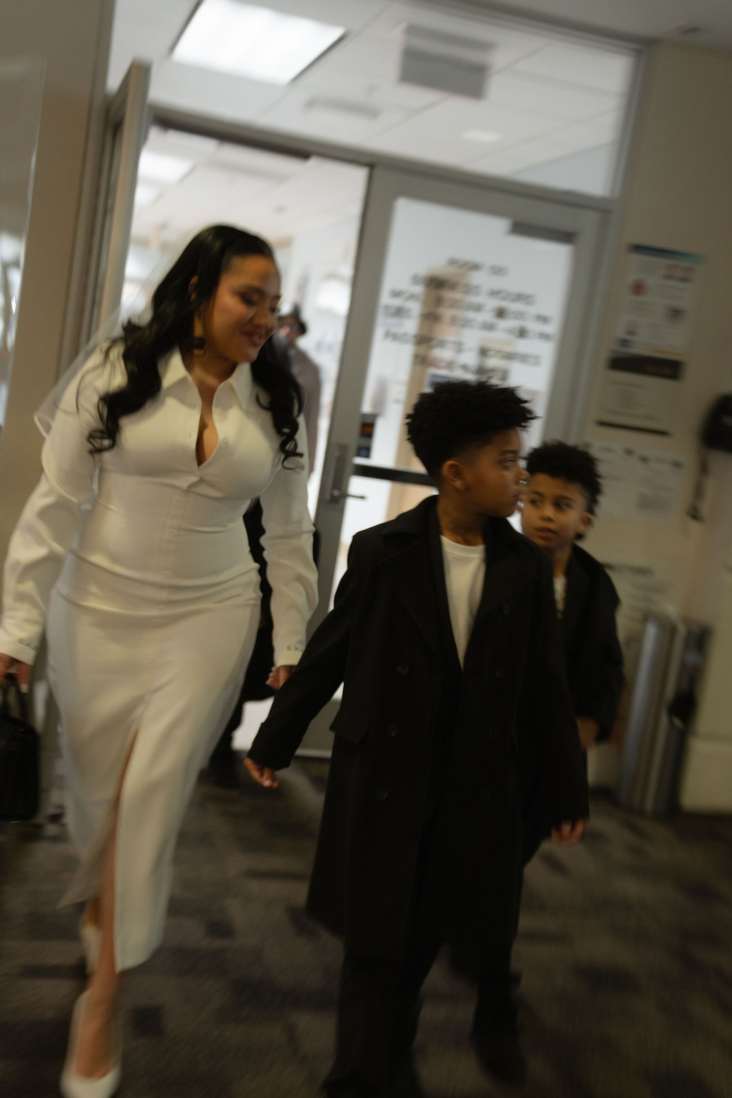 People walking together down a bright hallway in formal black and white attire.