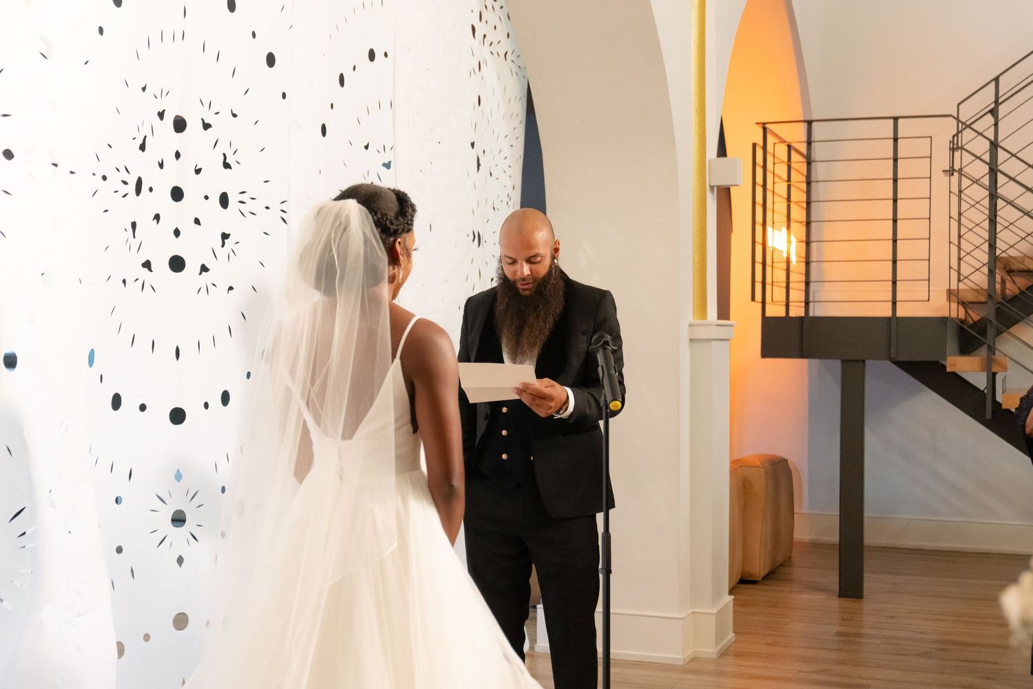 Wedding ceremony moments captured against white walls with artistic black dot patterns.