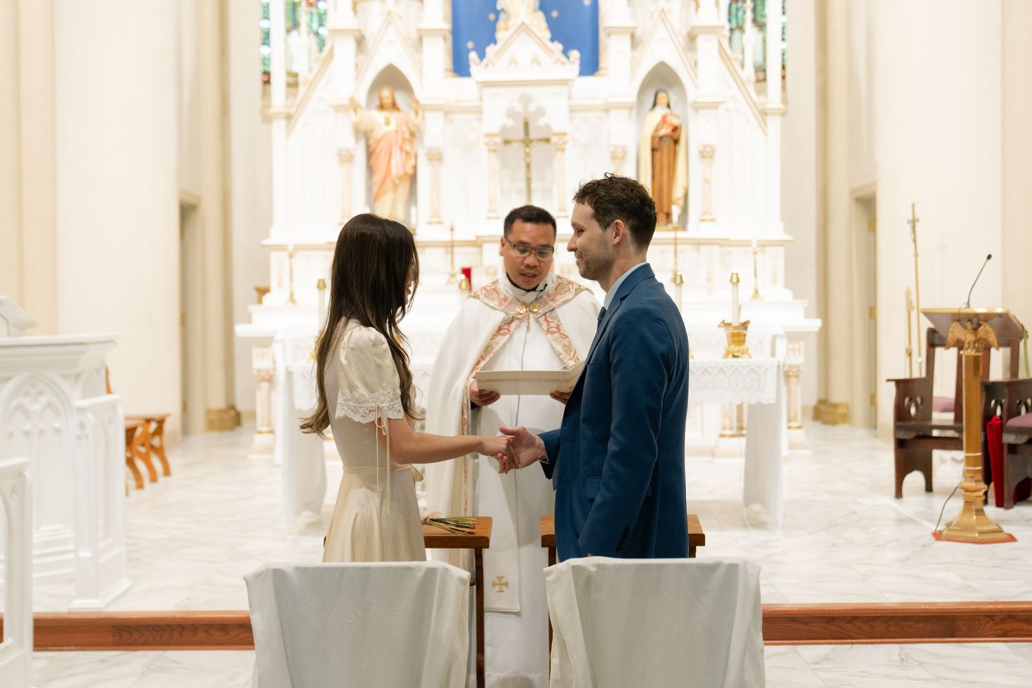 A couple shares an intimate moment in front of a church altar with stained glass windows.