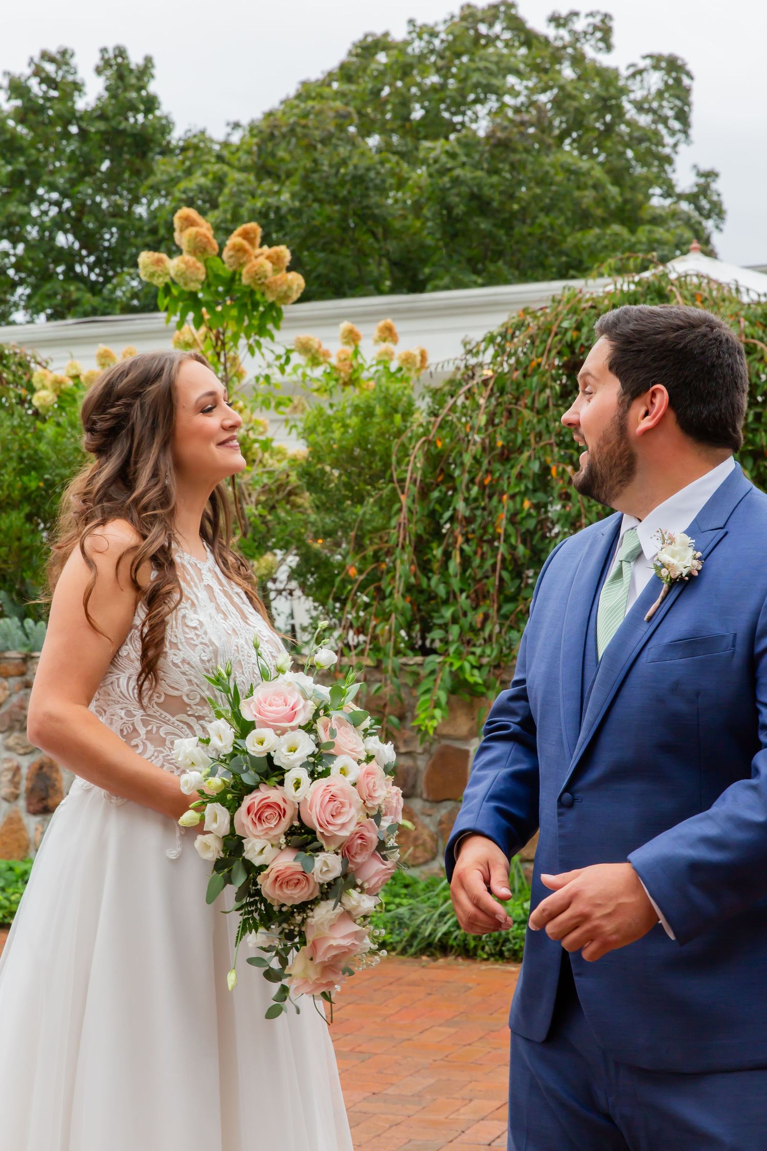 Bride and groom looking at each other beside a garden pond and waterfall.