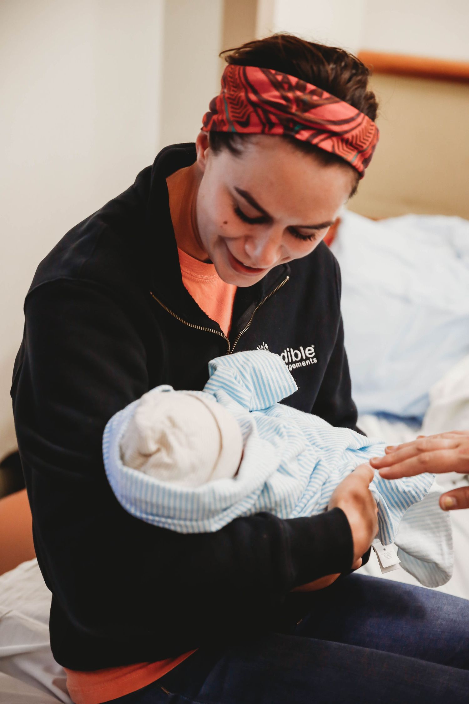 Mother looking down at her swaddled newborn in her arms in the hospital.