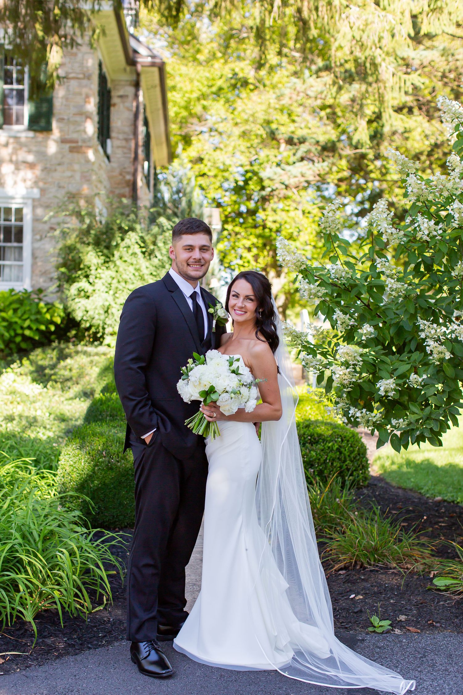 Bride and groom standing together in a leafy garden.